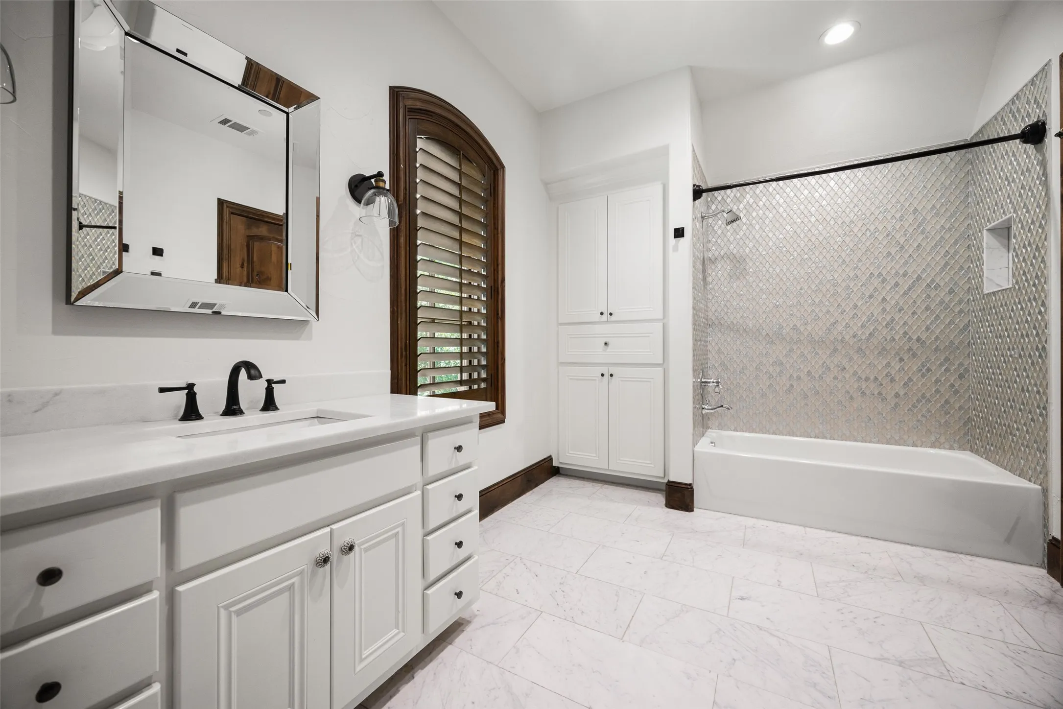 Bathroom featuring white cabinetry, a marble-finish countertop with an undermount sink, and matte black fixtures