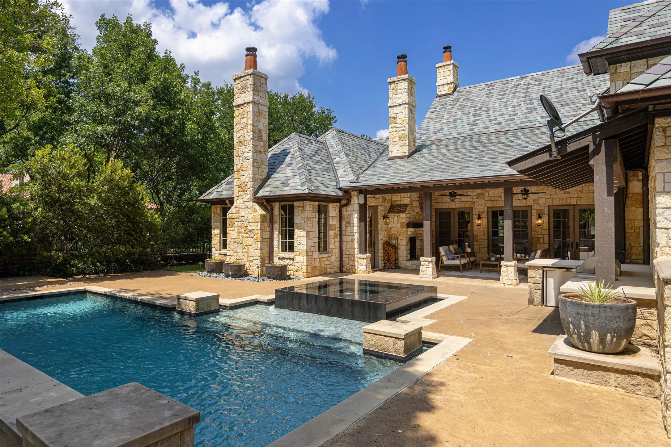 Expansive outdoor living area featuring a swimming pool, integrated spa, and a covered patio