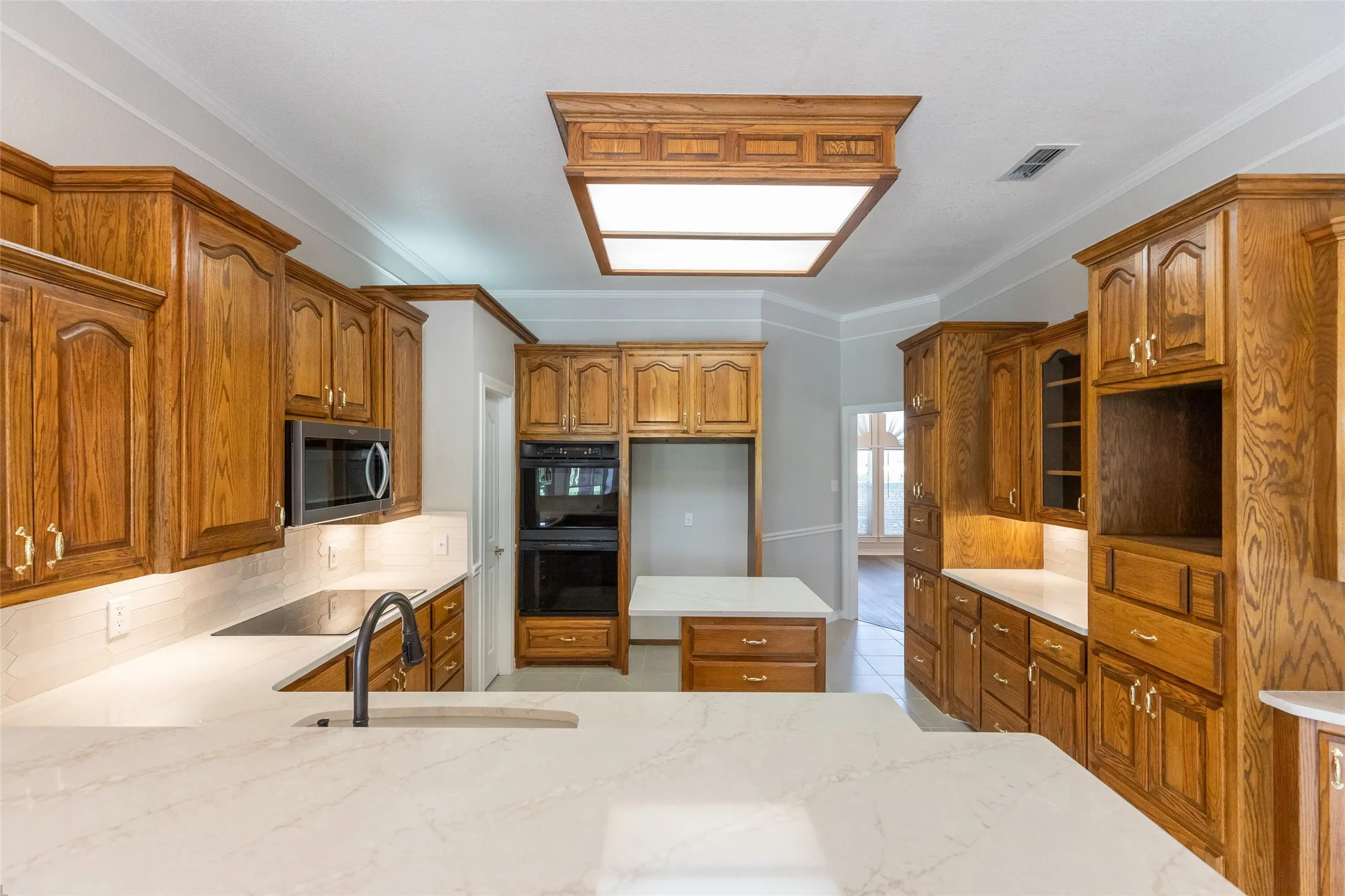 Gorgeous kitchen with oak cabinets, pull out drawers, double ovens (top is convection) and island with overhang for bar stool. The cubby to the right was built to house a TV.