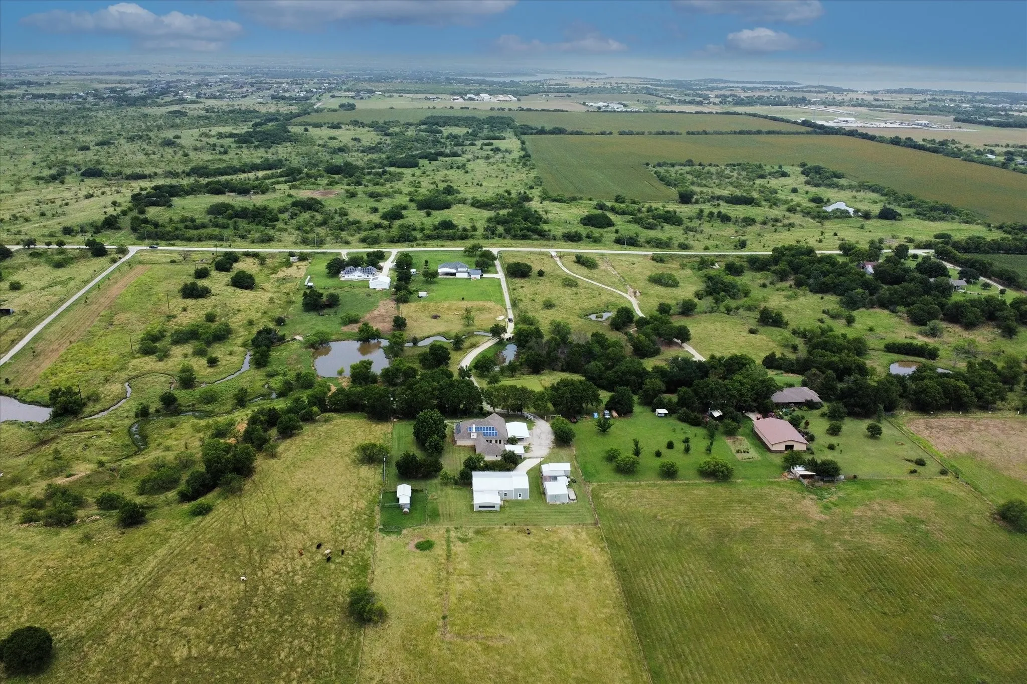 Expansive aerial rendering showcasing multiple residential structures, diverse cultivated fields, and natural waterways