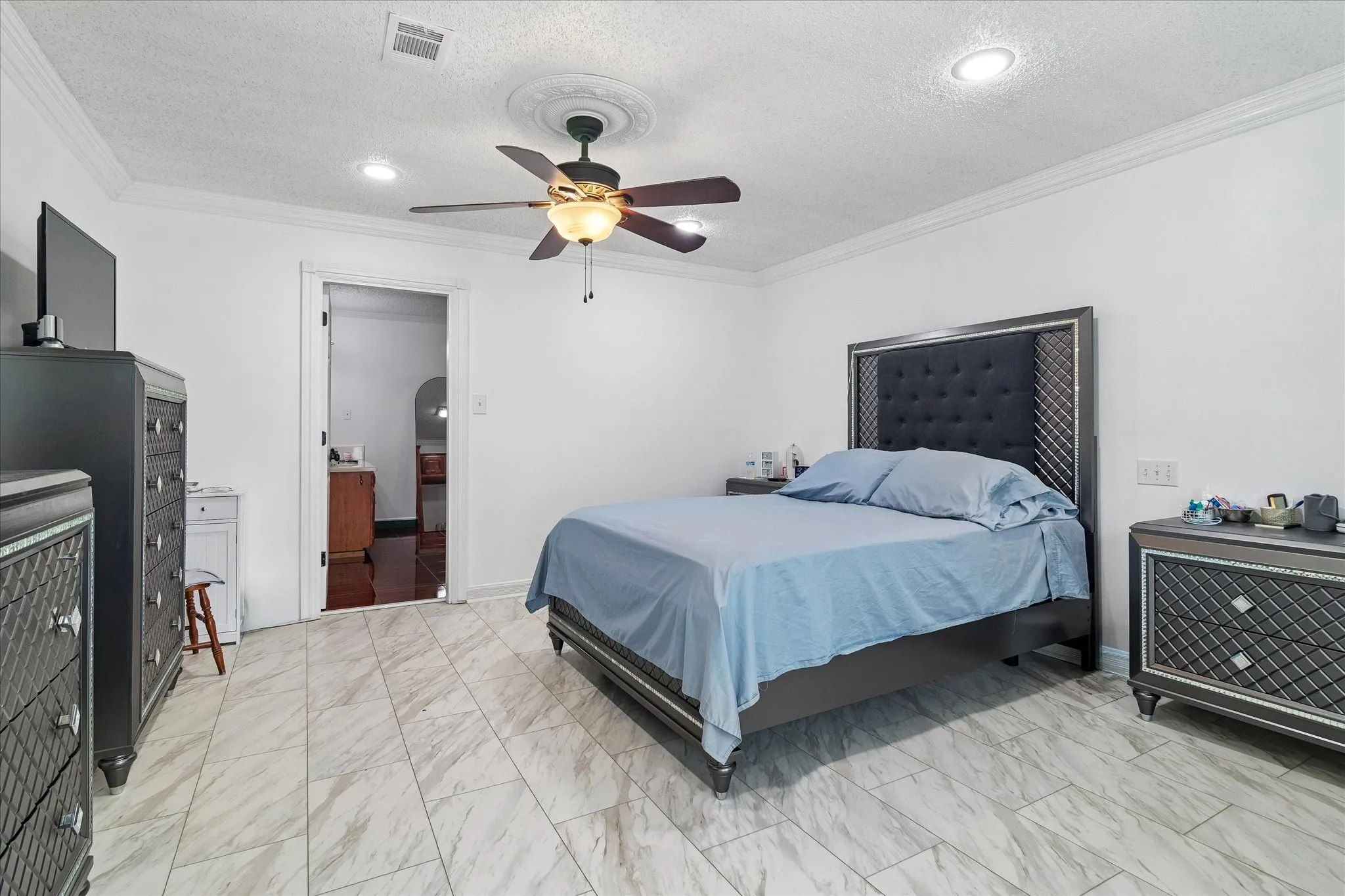 Spacious room featuring light-toned tile flooring, white walls, and crown molding