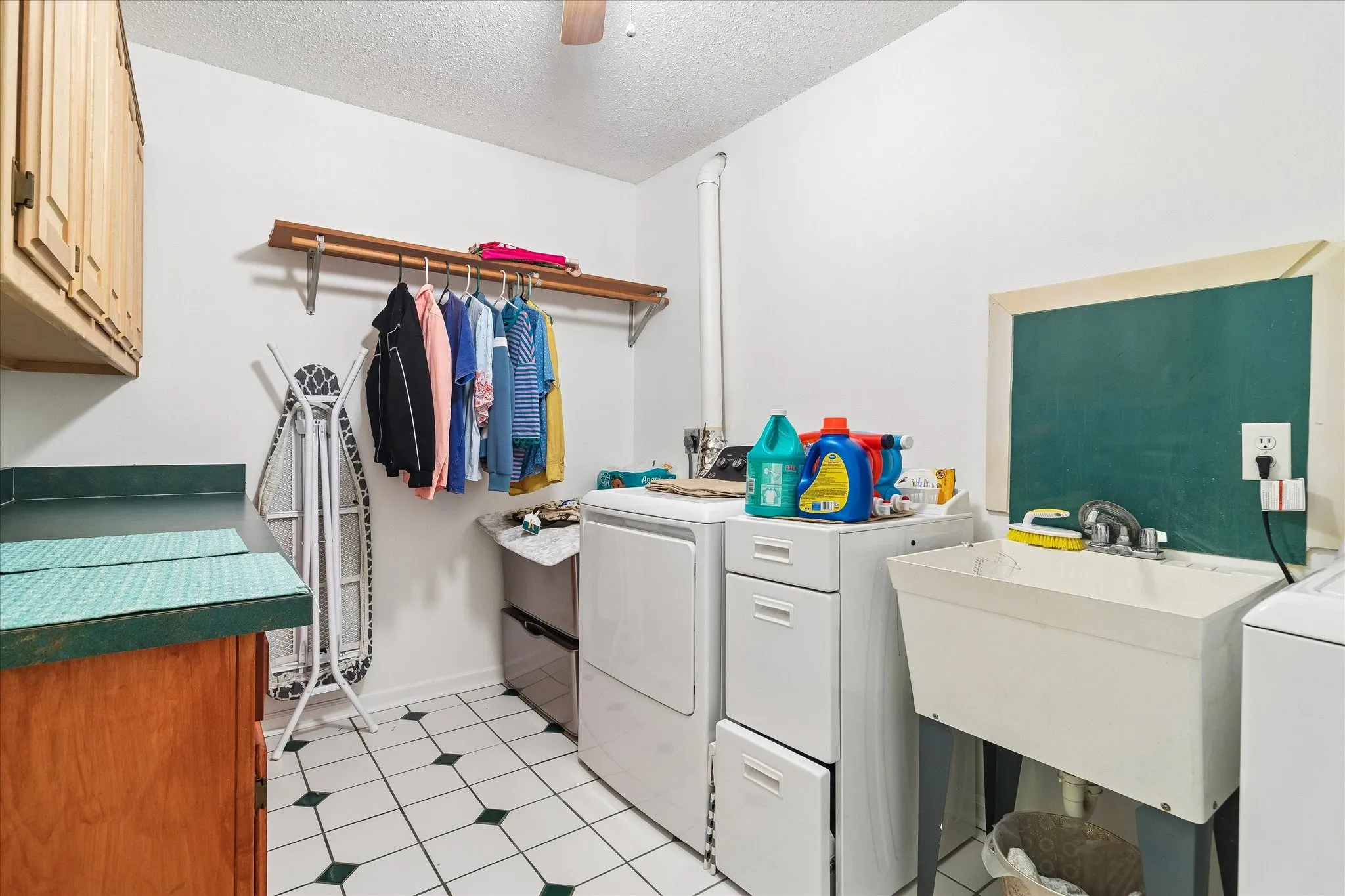 Dedicated laundry room featuring white and dark green checkered tile flooring