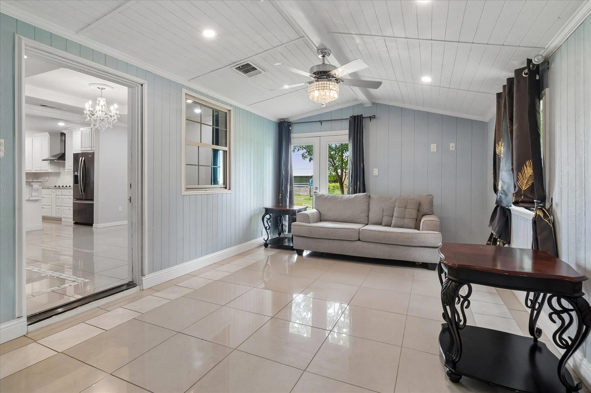 Spacious room with large format tile flooring, vaulted plank ceiling, recessed lighting, and a crystal chandelier ceiling fan