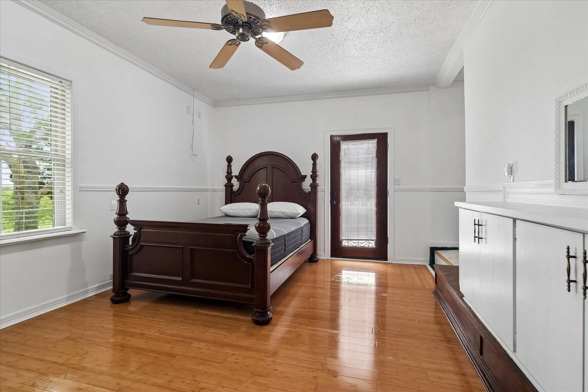 Bright interior with wood-finish flooring, a ceiling fan with light fixture, and a window with blinds