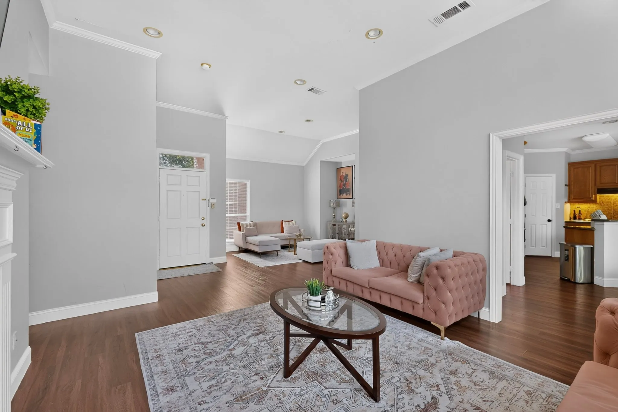 Open-concept living space featuring wood-finish flooring, recessed lighting, and crown molding