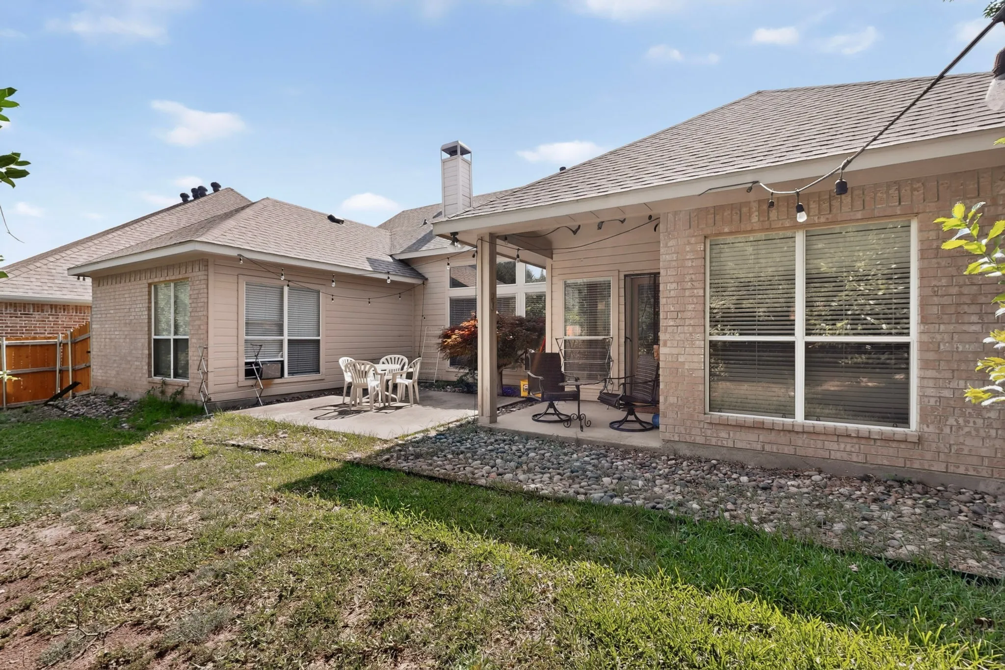Rear exterior featuring a brick facade, covered patio, and additional concrete patio space