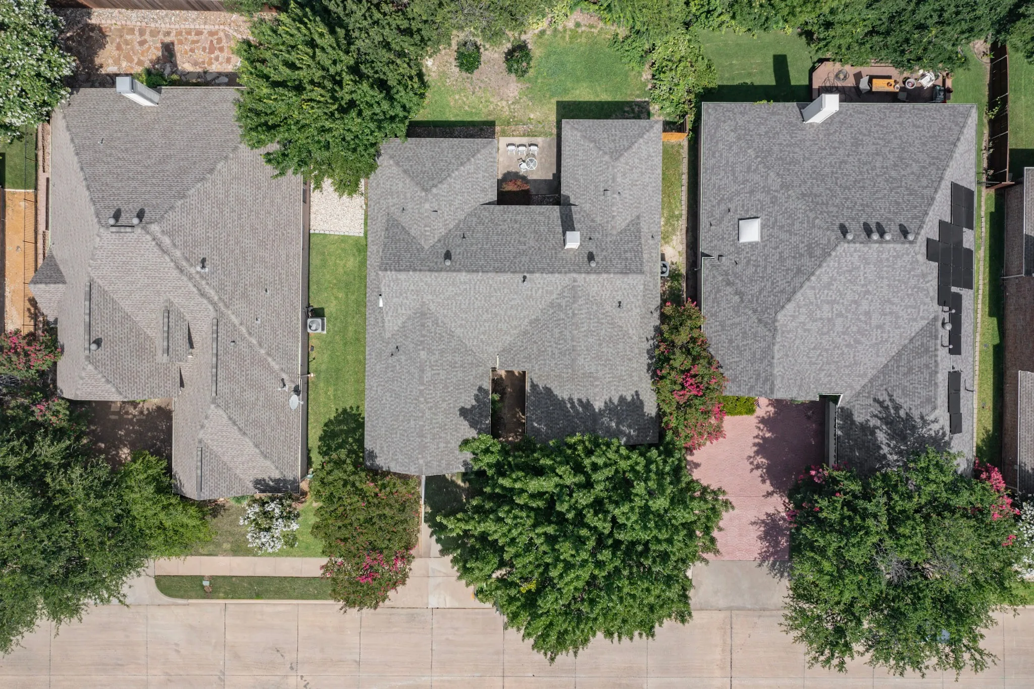 Aerial perspective showcasing three properties with gray shingle roofing