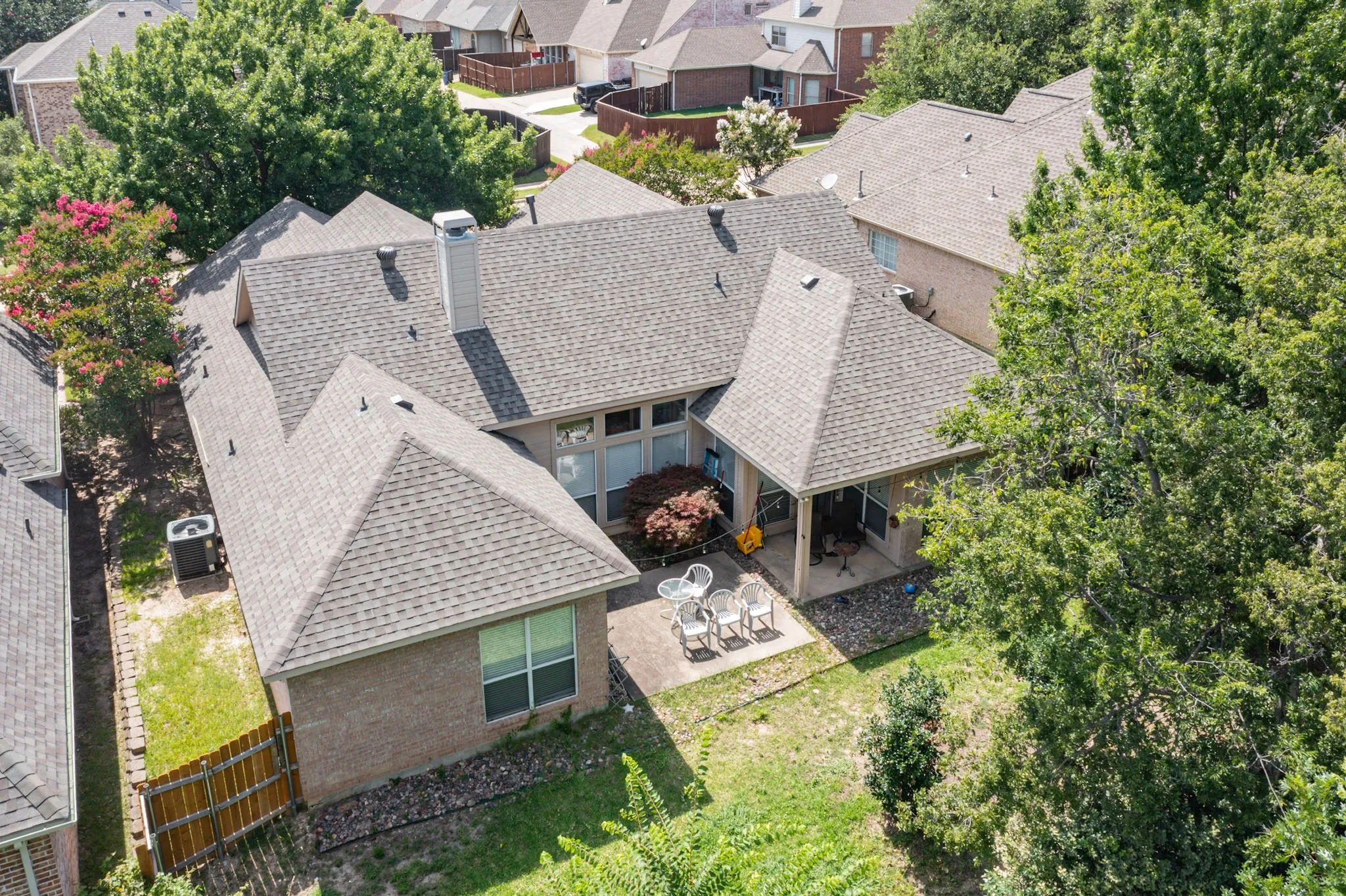 Rear exterior featuring a covered patio, brick facade, and multiple gables