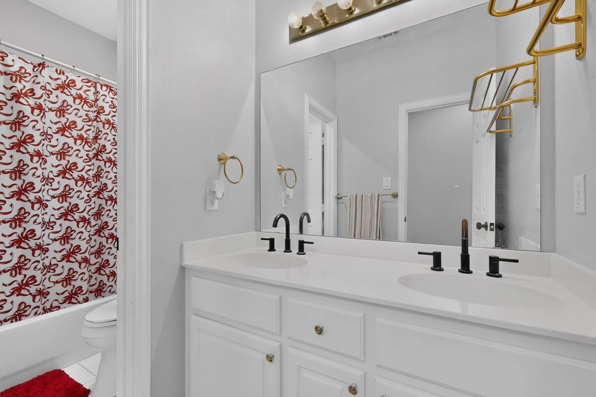 Bathroom featuring a dual vanity with white cabinetry, white countertops, and black fixtures