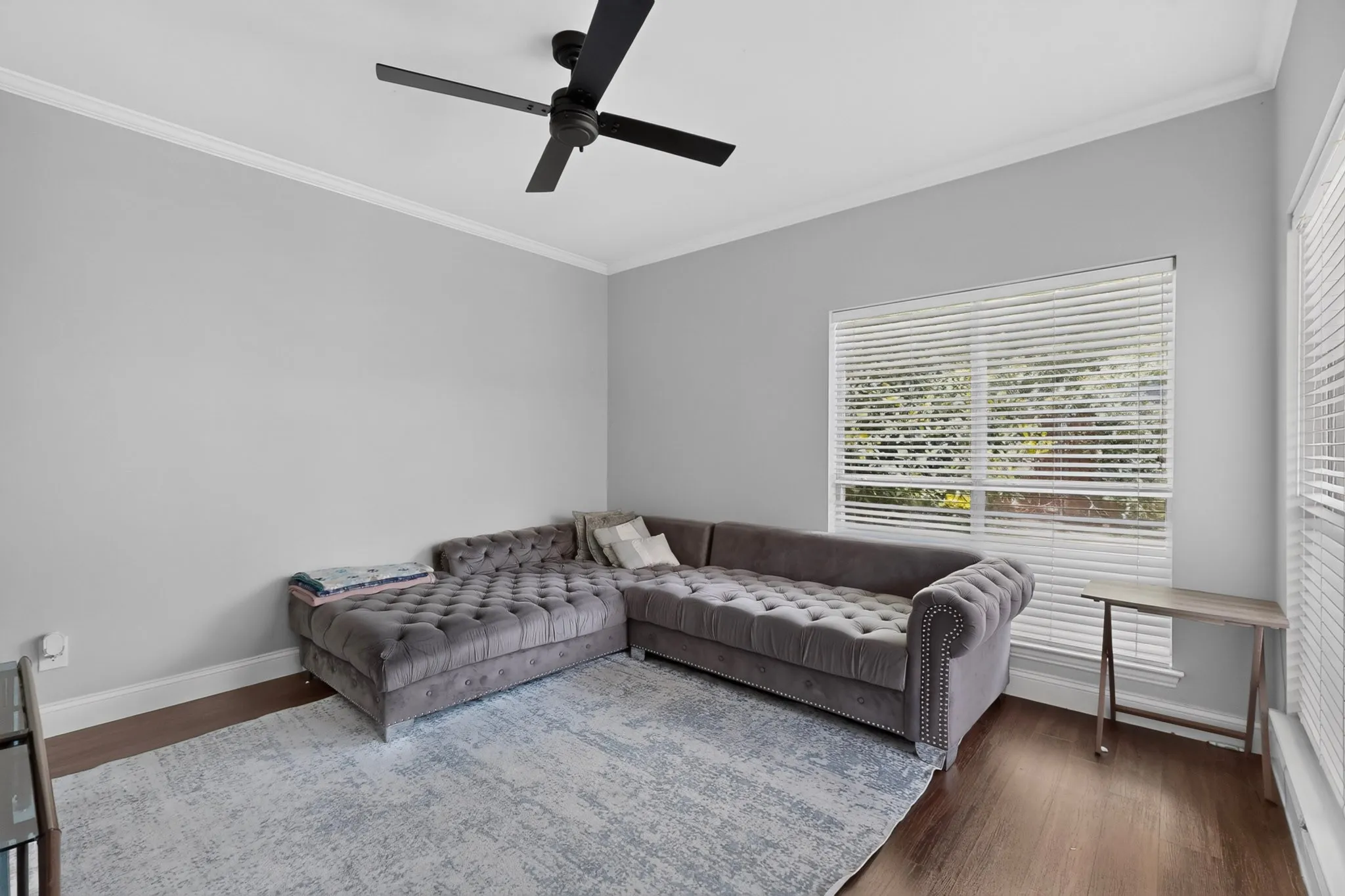 Spacious room featuring wood-finish flooring, light grey walls, and crown molding