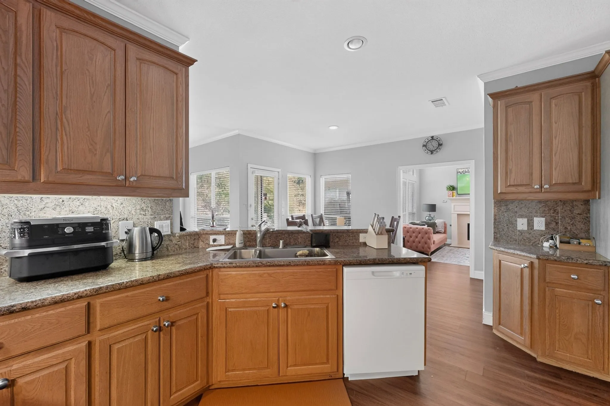 Kitchen featuring wood cabinetry, granite countertops, an undermount sink, and wood-finish flooring
