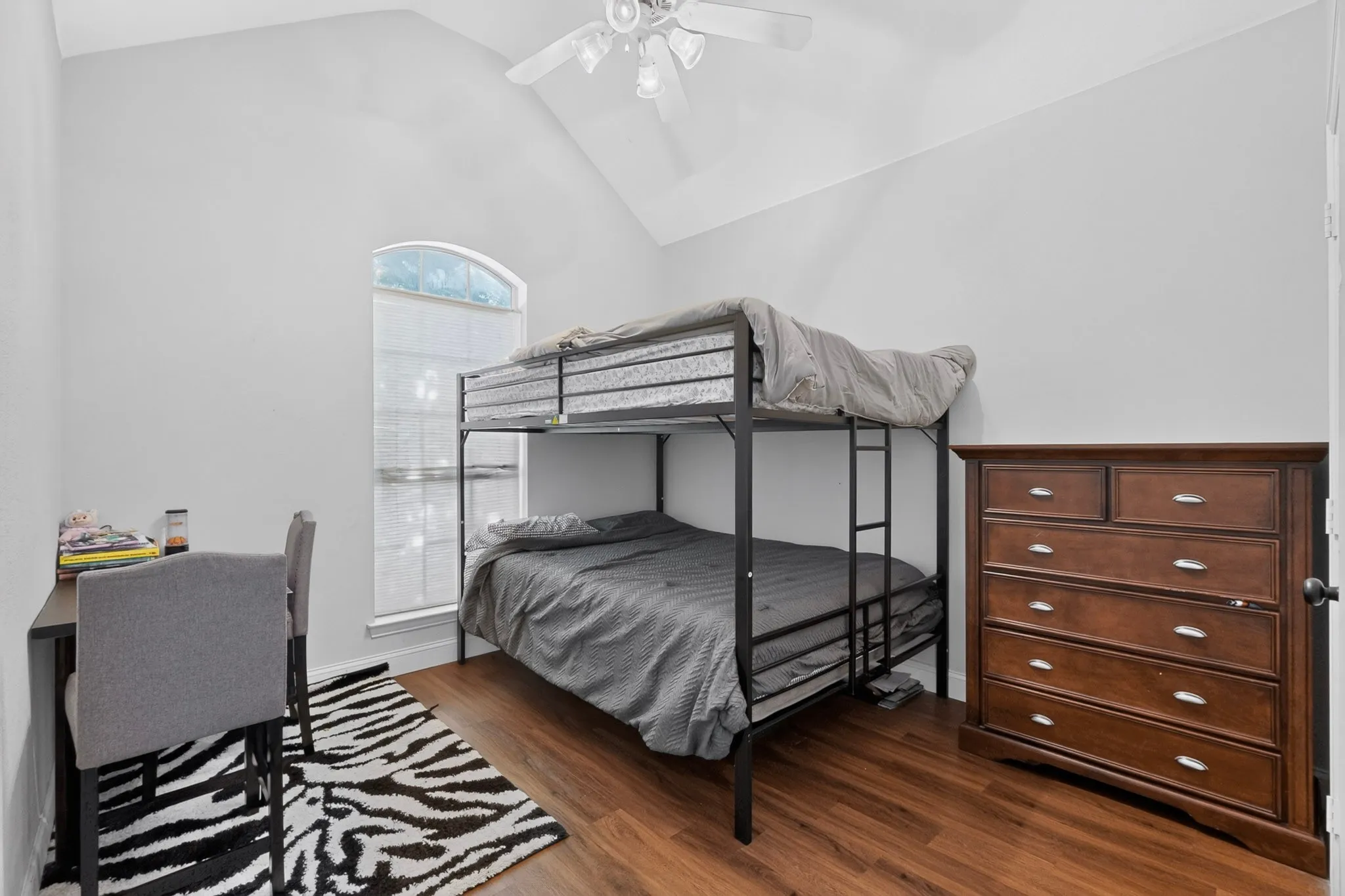 Room featuring a vaulted ceiling with a ceiling fan, wood-finish flooring, and an arched window