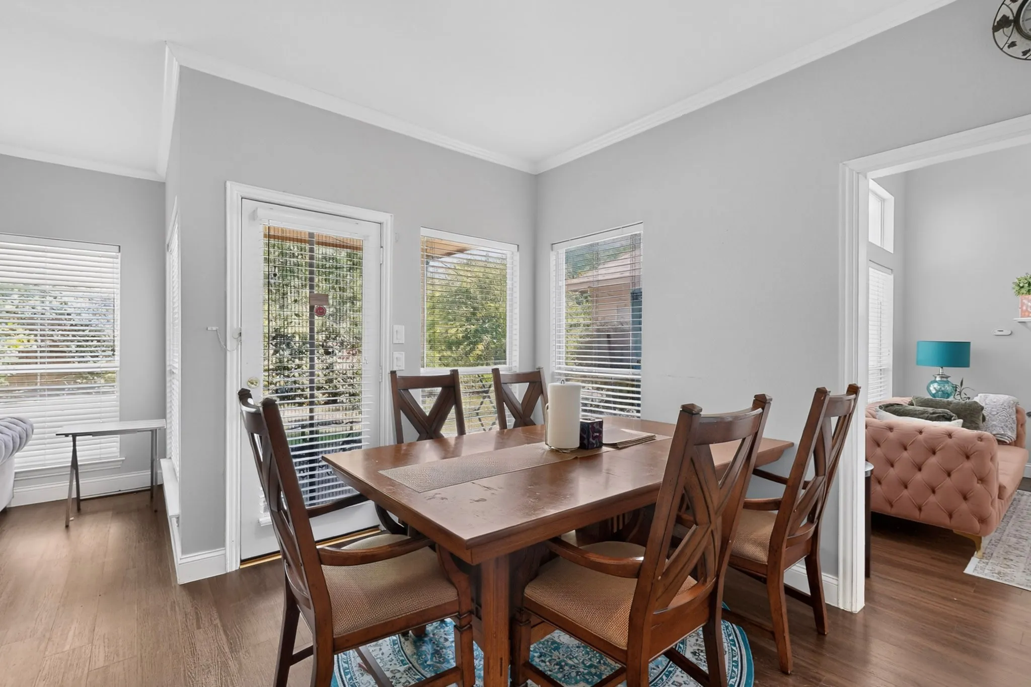 Dining area with wood-finish flooring, light gray walls, and white crown molding