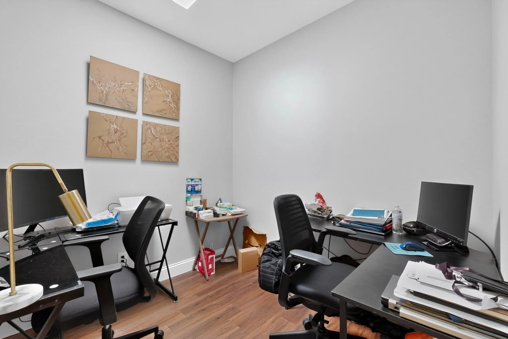 Room with wood-finish flooring, light grey painted walls, and white baseboards