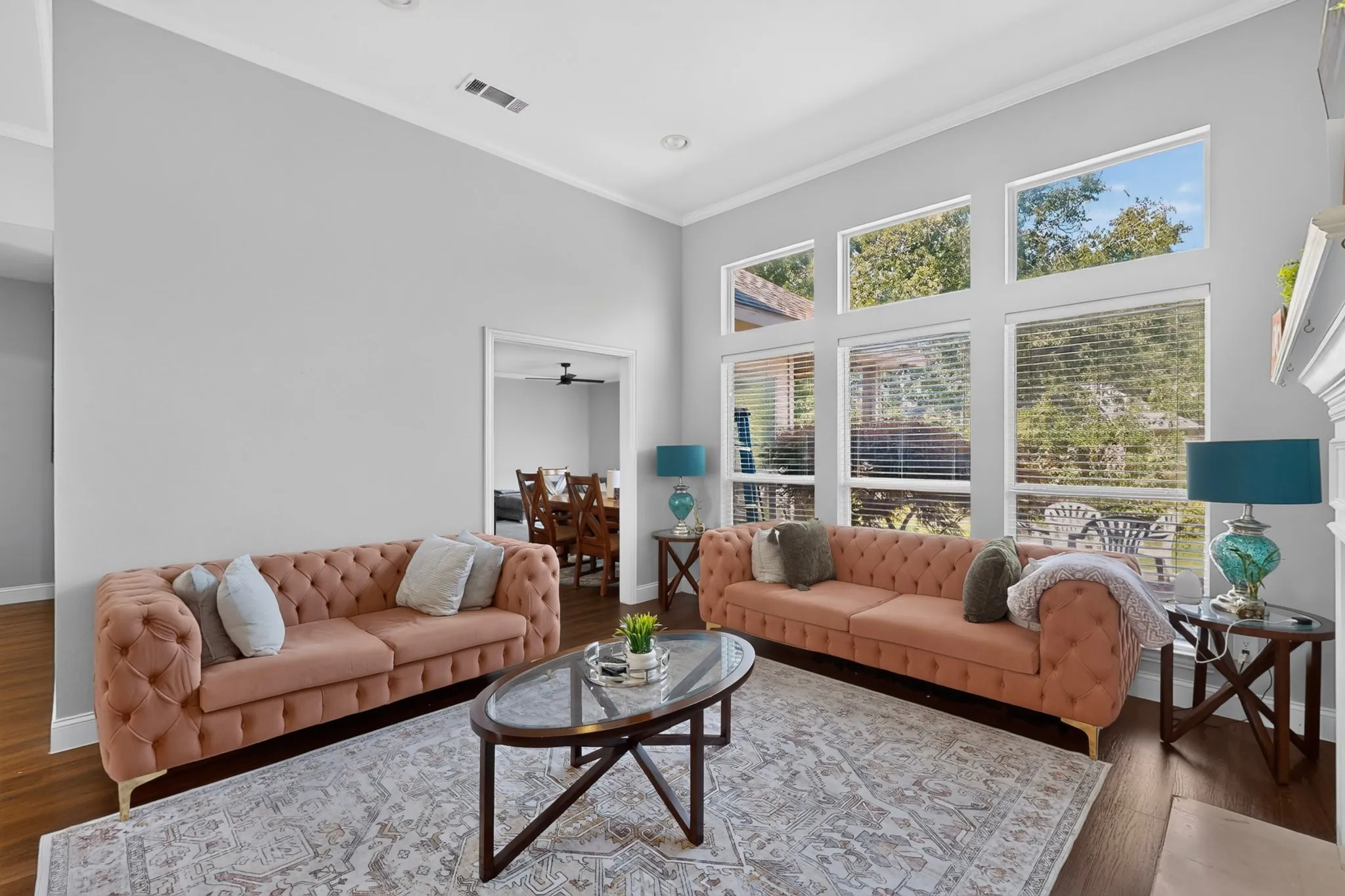 Living room with high ceilings, wood-finish flooring, and a decorative area rug
