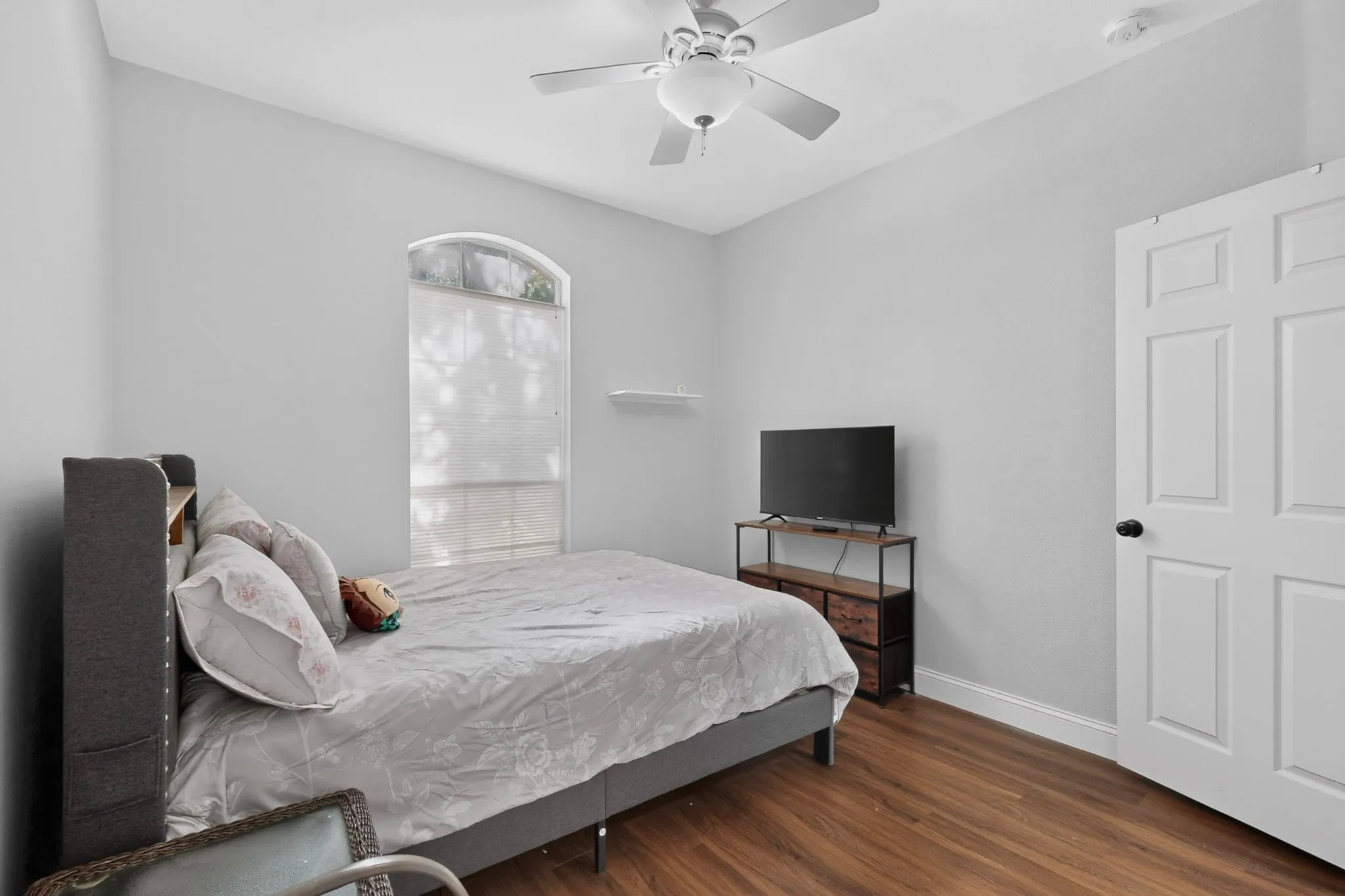 Bedroom featuring wood-finish flooring, a vaulted ceiling, and an arched window