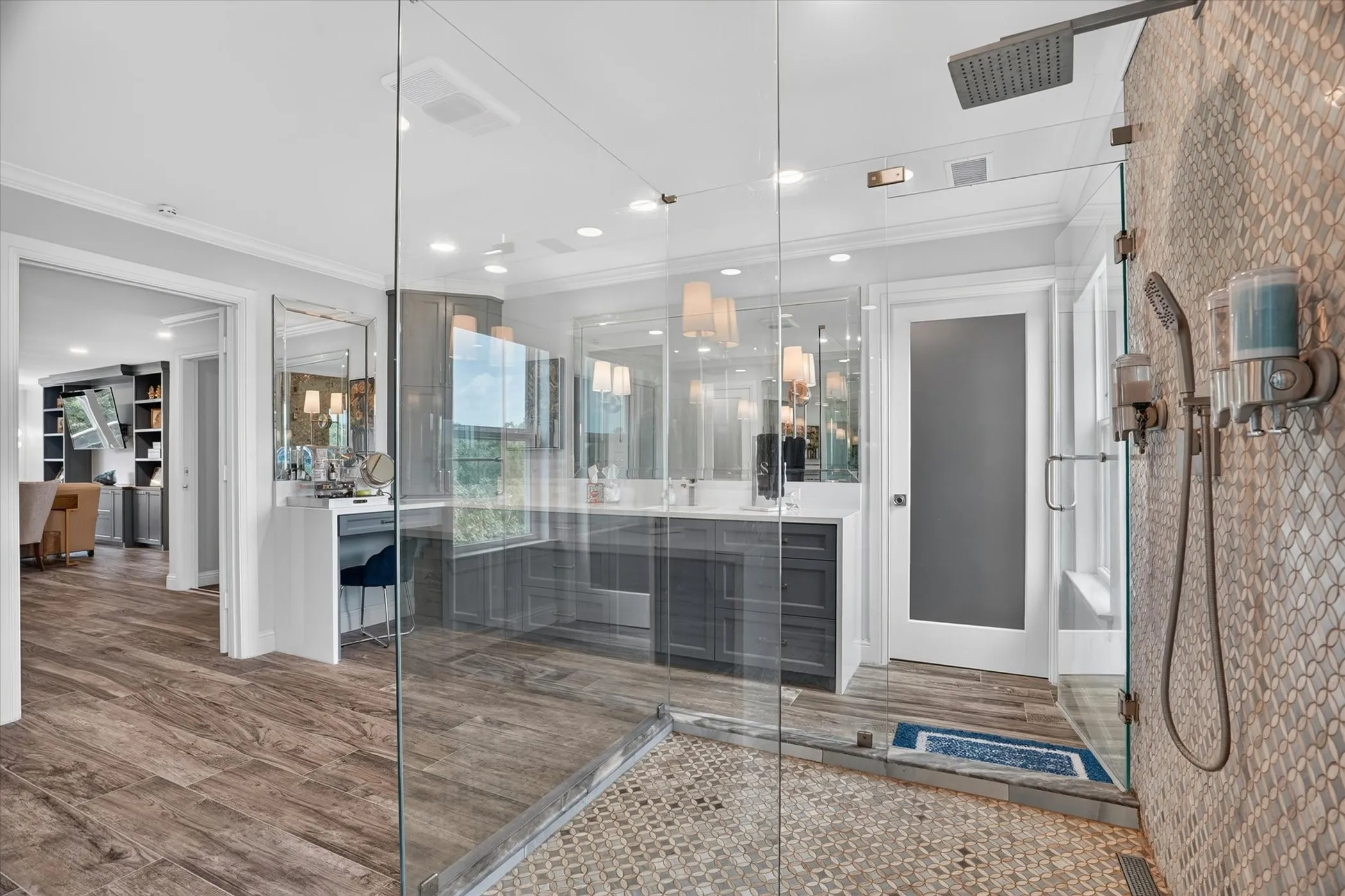 Spacious bathroom featuring a glass-enclosed shower with a rainfall showerhead and handheld sprayer, mosaic tile shower surround, and wood-finish flooring