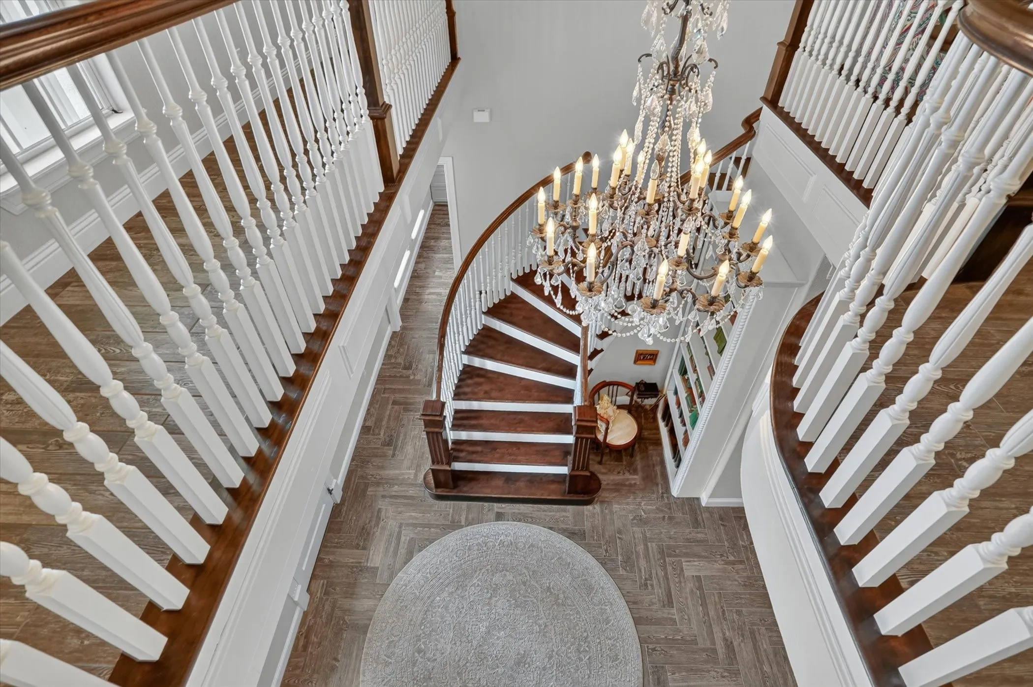 Grand curved staircase featuring dark wood treads and white balusters
