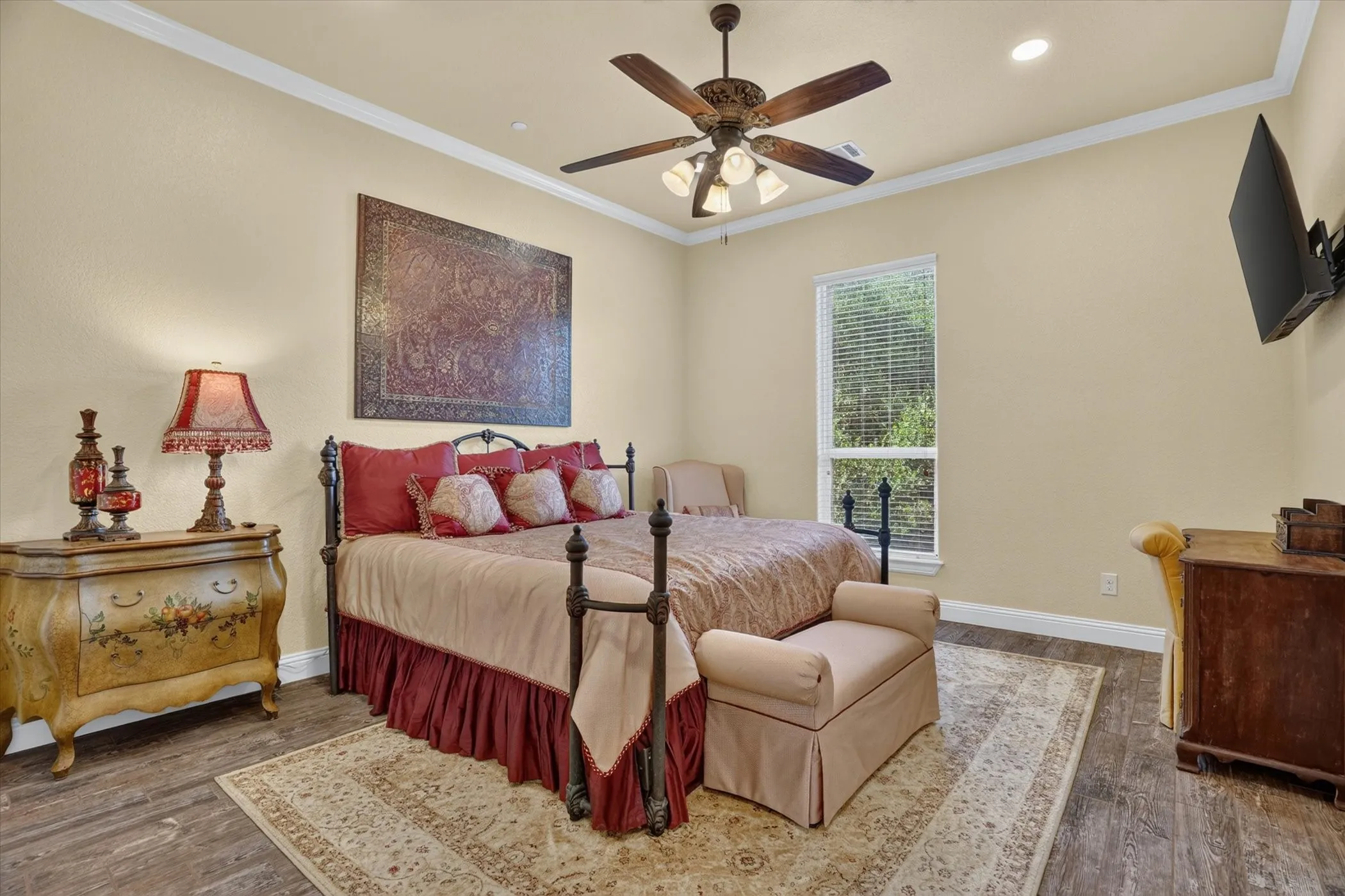 Spacious room featuring wood-finish flooring, a ceiling fan with integrated lighting, a single pane window with horizontal blinds, and crown molding