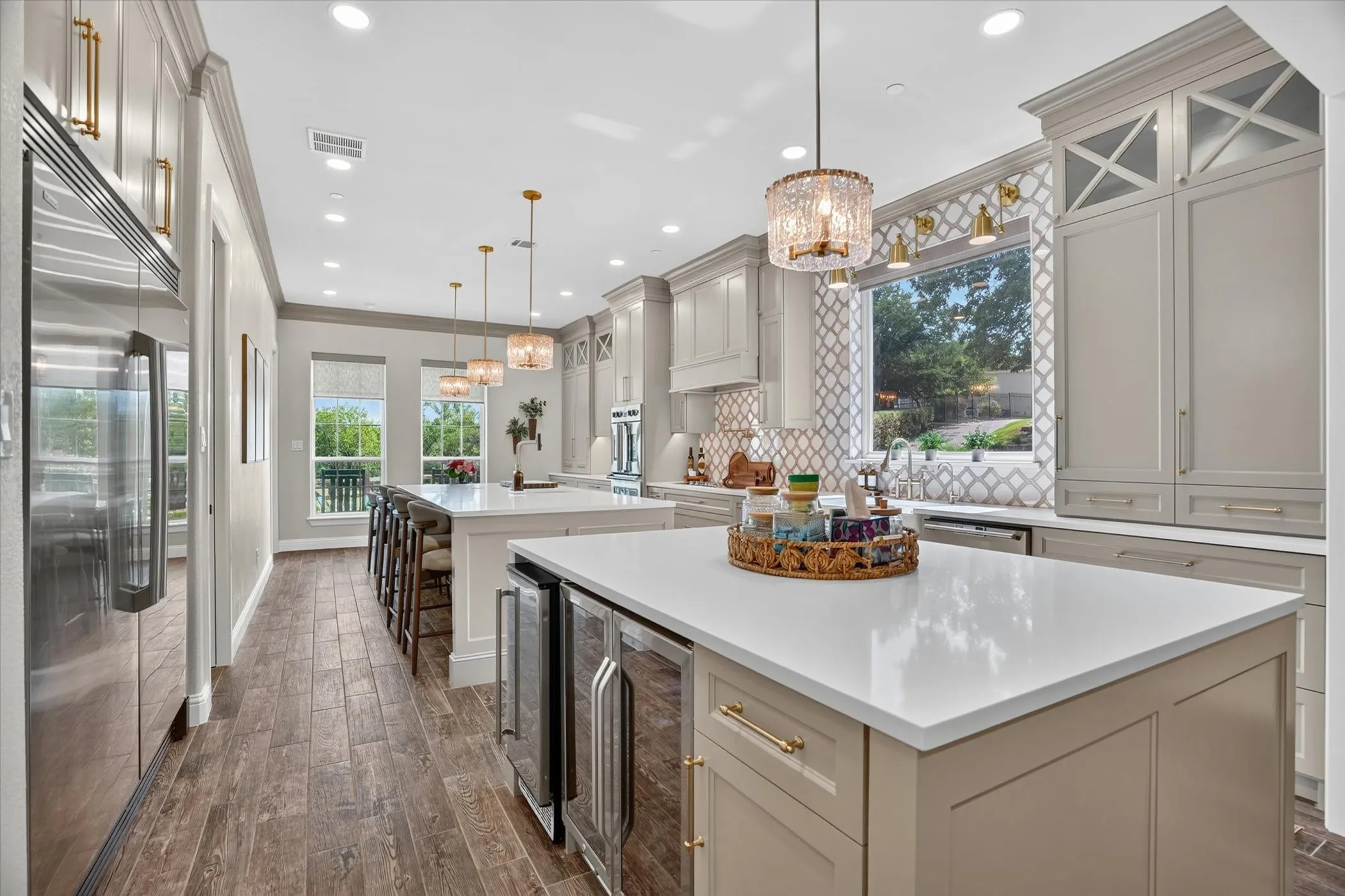 Spacious kitchen featuring two islands with white countertops, integrated beverage refrigerators, and recessed lighting