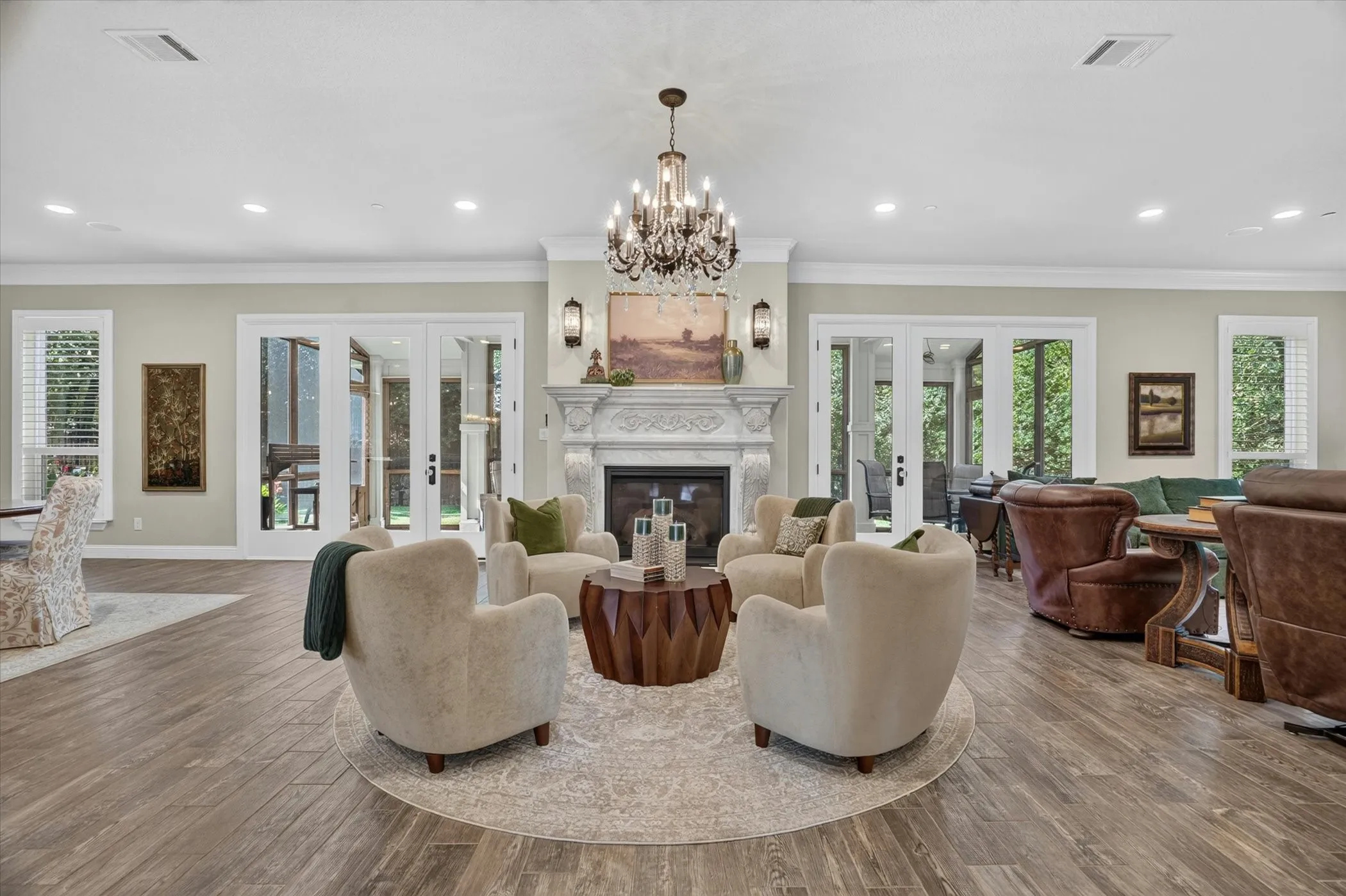 Spacious living area featuring an ornate fireplace with mantel, wood-finish flooring, and multiple sets of glass-paneled French doors