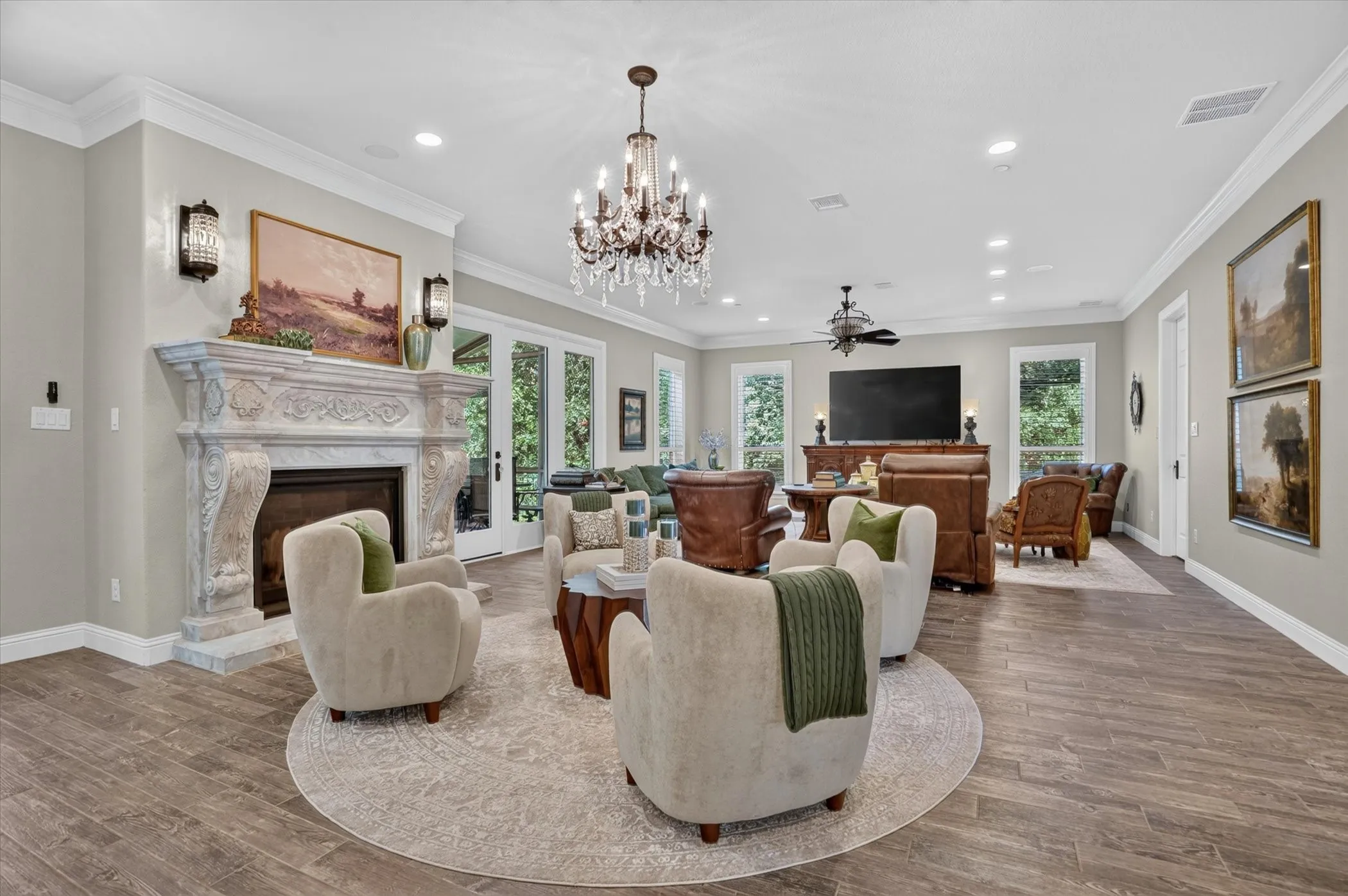 Spacious living area featuring a carved stone fireplace, wood-finish flooring, and a chandelier