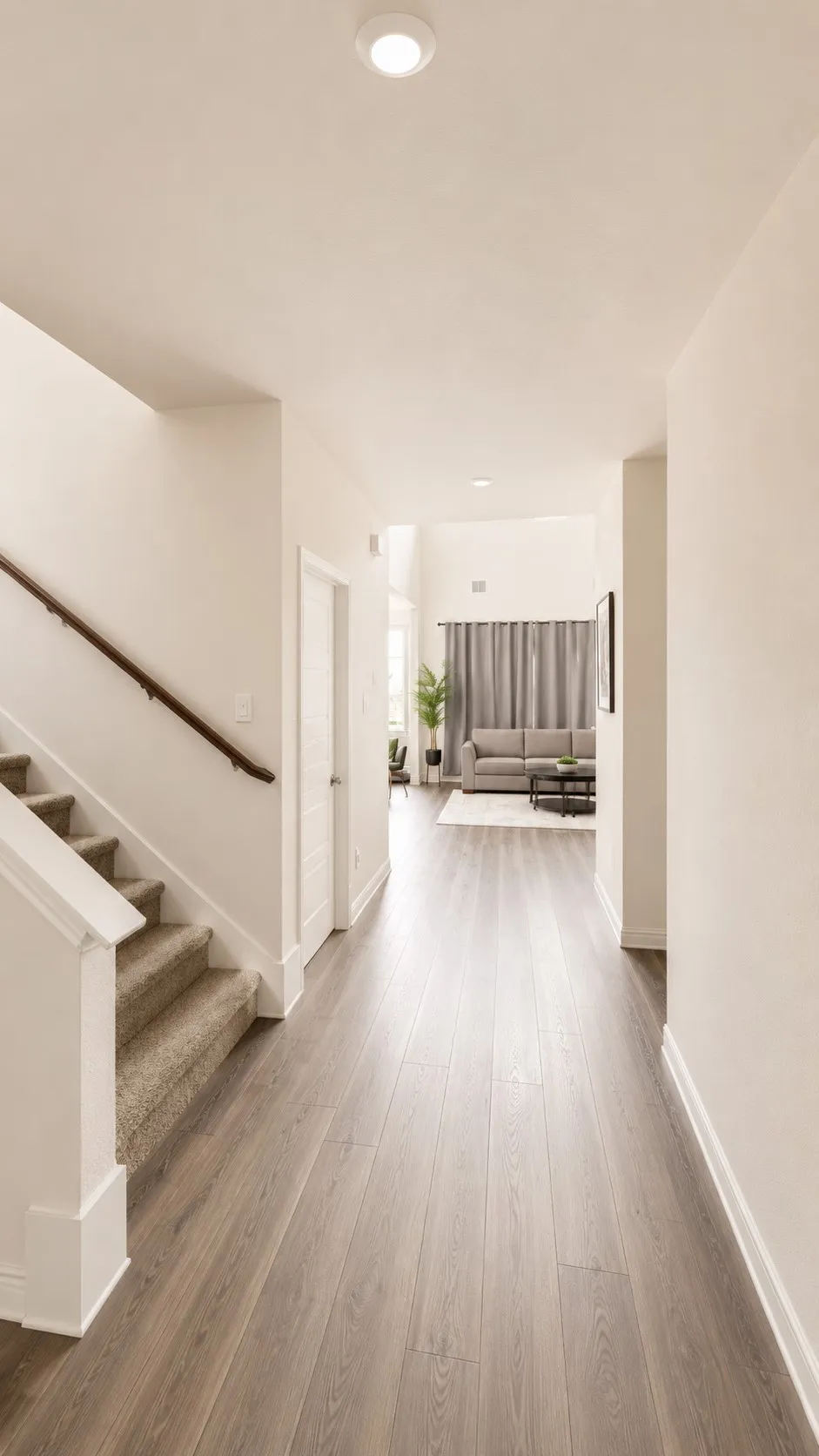 Hallway featuring wood-finish flooring, recessed lighting, white baseboards, and a carpeted staircase with a wood handrail
