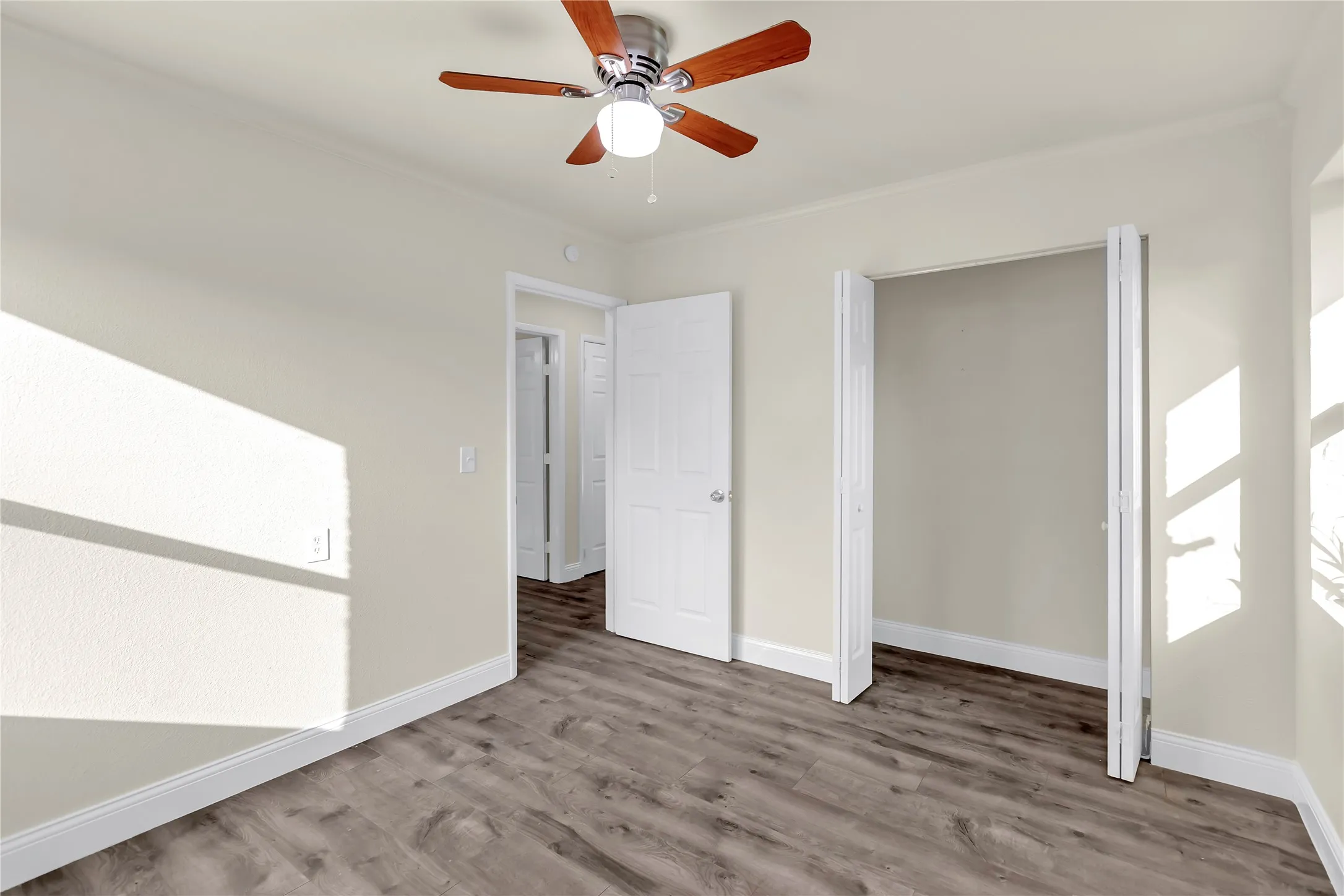 Interior room featuring wood-finish flooring, light neutral wall paint, and white baseboards
