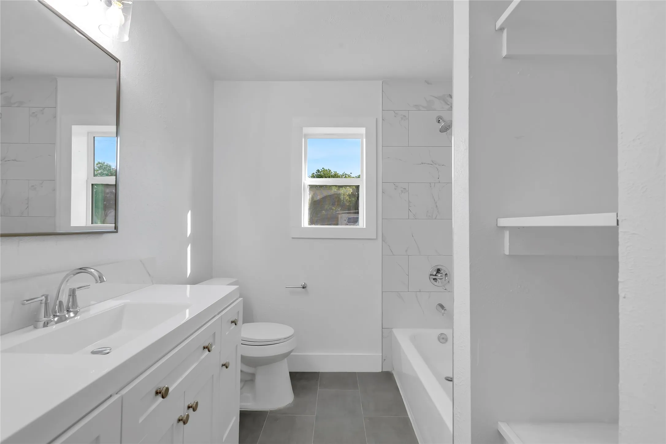 Bathroom featuring a single vanity with a white countertop, chrome fixtures, and a rectangular mirror