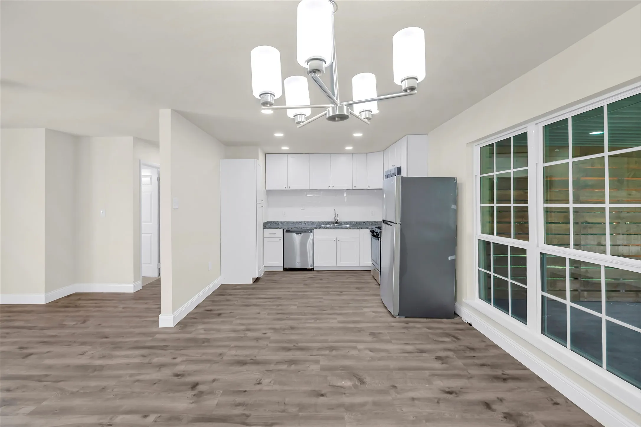 Open-concept interior featuring wood-finish flooring, a modern chandelier, and recessed lighting