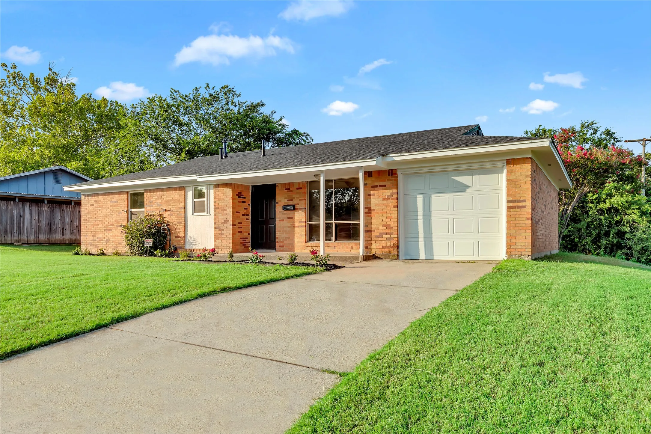 Brick exterior with white trim, featuring a white garage door and a concrete driveway