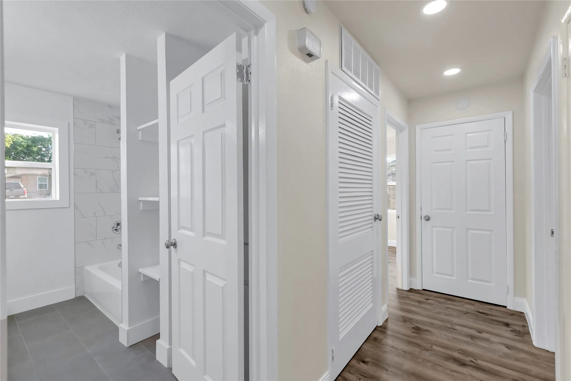 Hallway featuring wood-finish flooring, recessed lighting, and six-panel doors
