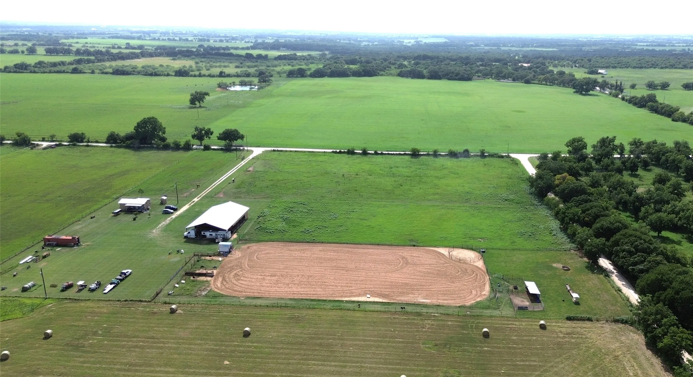 Expansive agricultural property featuring a large barn, additional outbuilding, and an outdoor riding arena