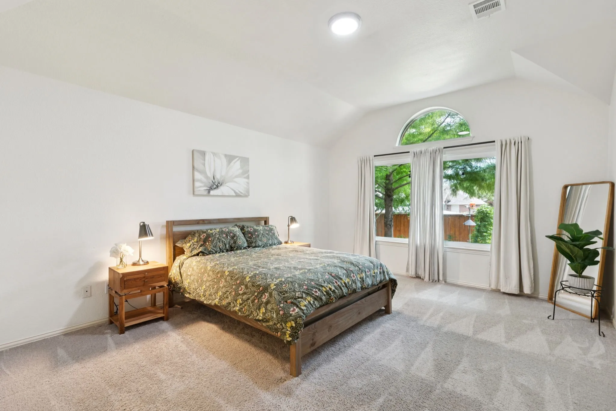The primary bedroom offers views of the backyard, large walk in closet, vaulted ceiling, carpet and an en suite bath.