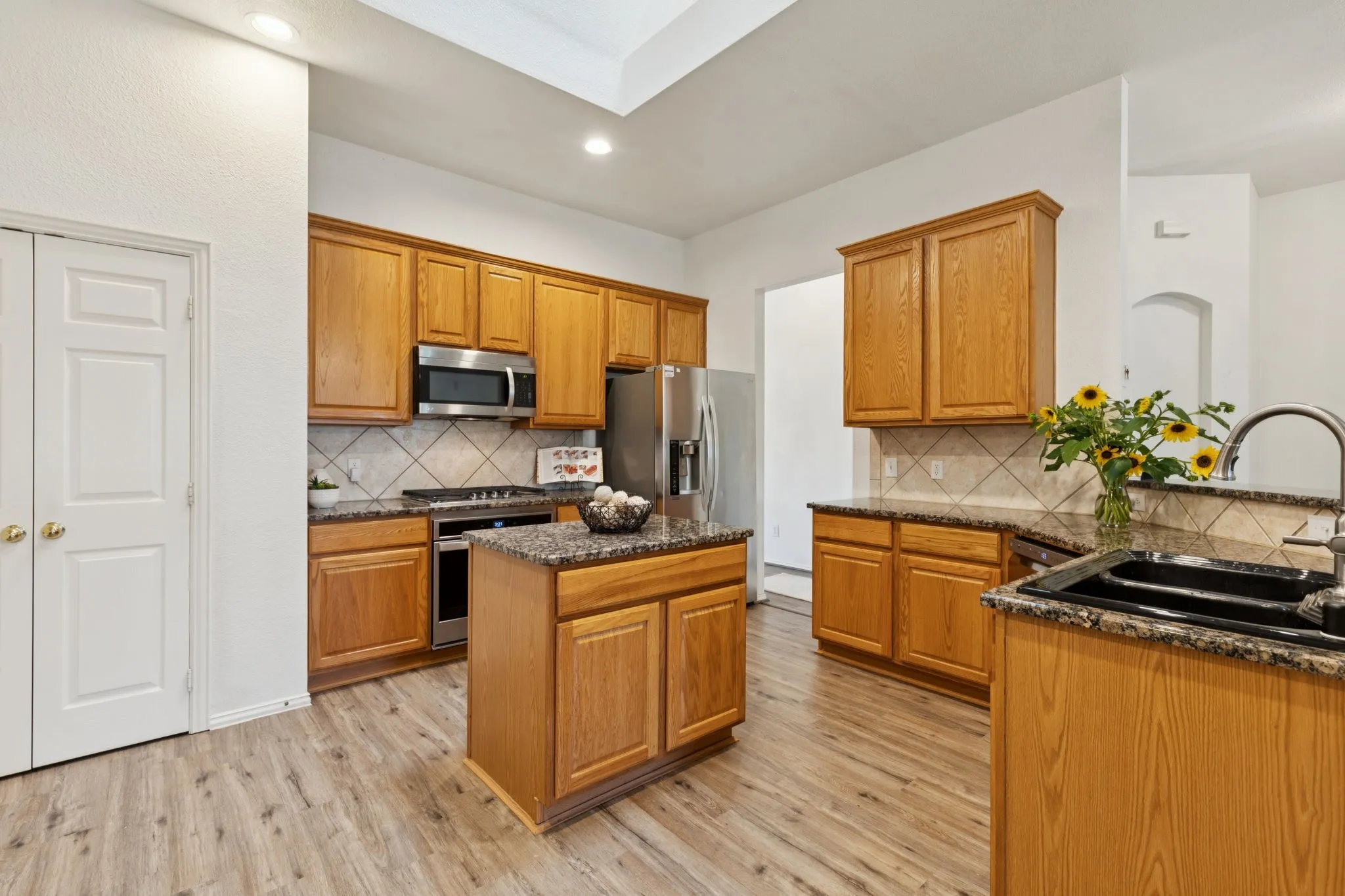 The spacious kitchen is in the heart of the home. Granite countertops with tile backspash give ample prep space. The island gives additional storage and another work area. Other features of the kitchen include gas cooktop, stainless appliances, recessed lighting, laminate flooring and a pantry.