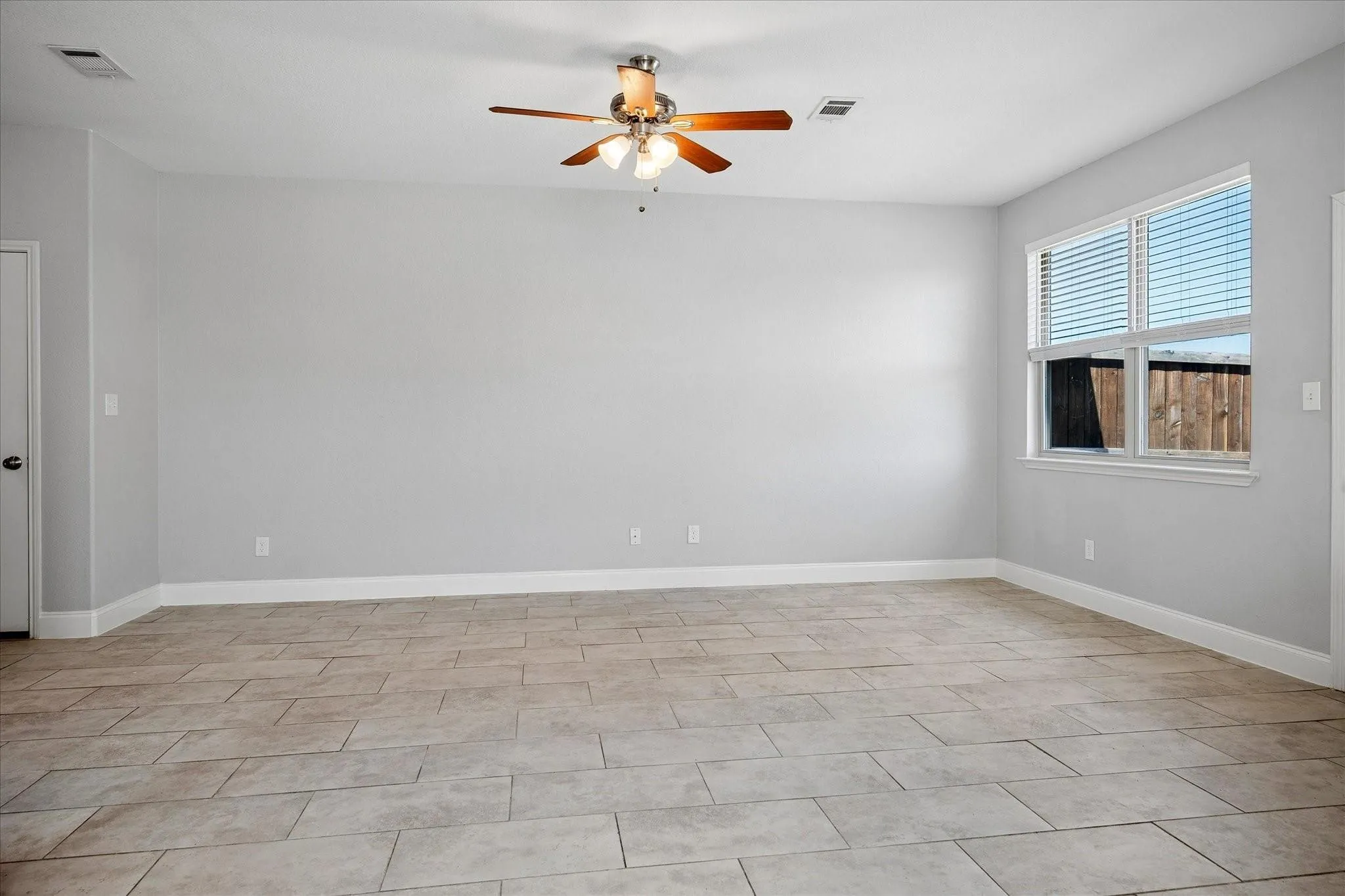 Spacious room featuring neutral-toned tile flooring, light gray walls, and white trim