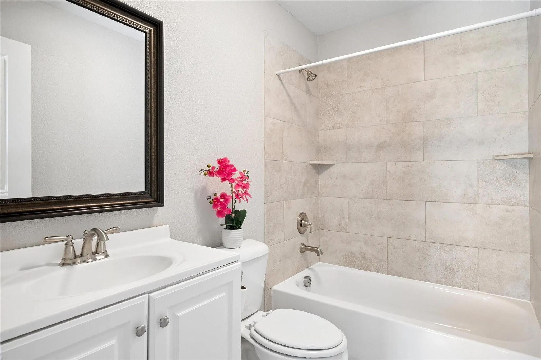 Bathroom featuring a white vanity with a ceramic sink, brushed nickel faucet, framed mirror, and a toilet