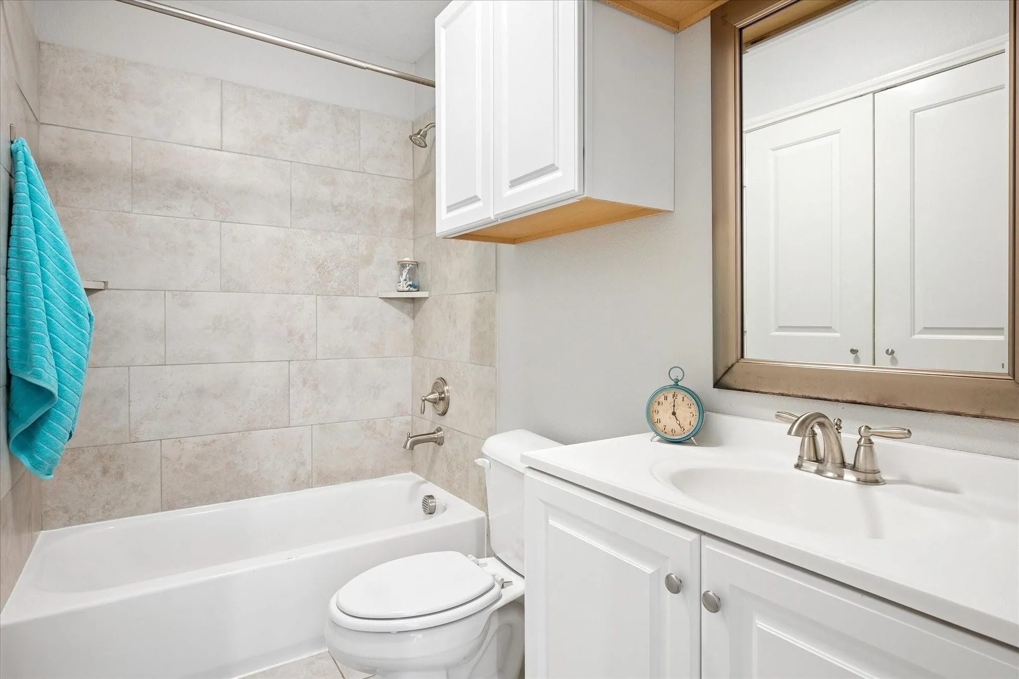 Full bathroom featuring a white vanity with integrated sink, brushed nickel faucet, and framed mirror