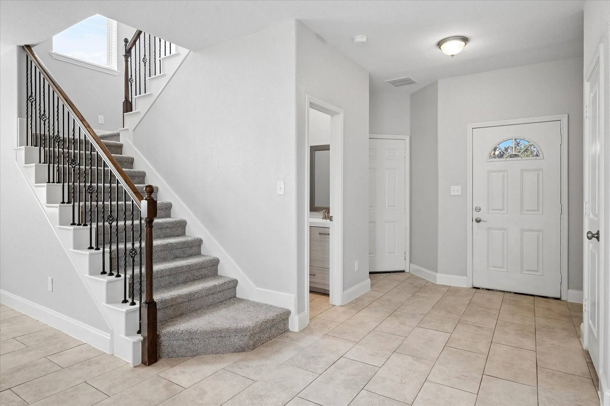 Foyer featuring a grand staircase with wrought iron balusters and a dark wood handrail