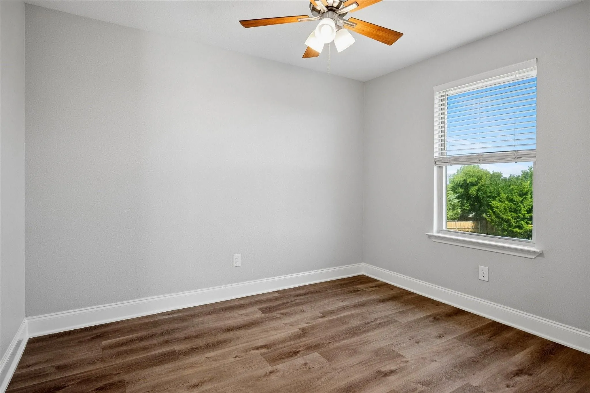Room featuring wood-finish flooring, light gray wall paint, and white baseboards