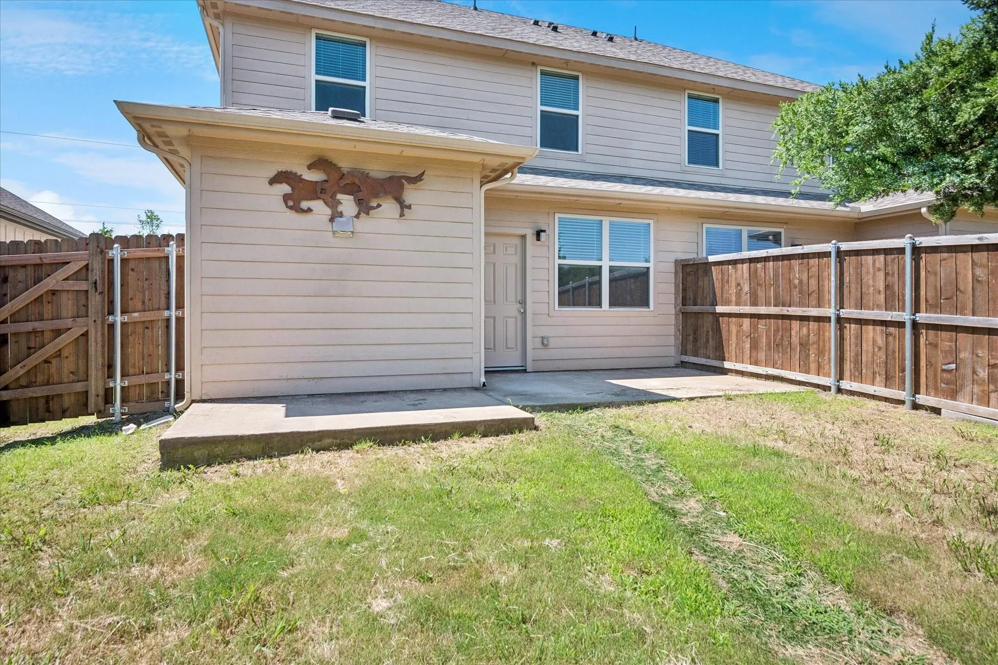 Private outdoor area featuring a concrete patio, wood fencing, and a grassy expanse