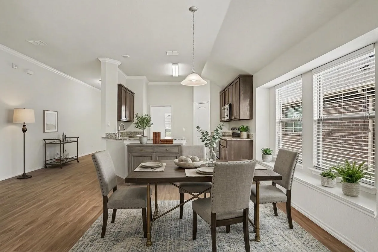 Virtually staged dining area featuring wood-finish flooring, a contemporary overhead light fixture, and crown molding