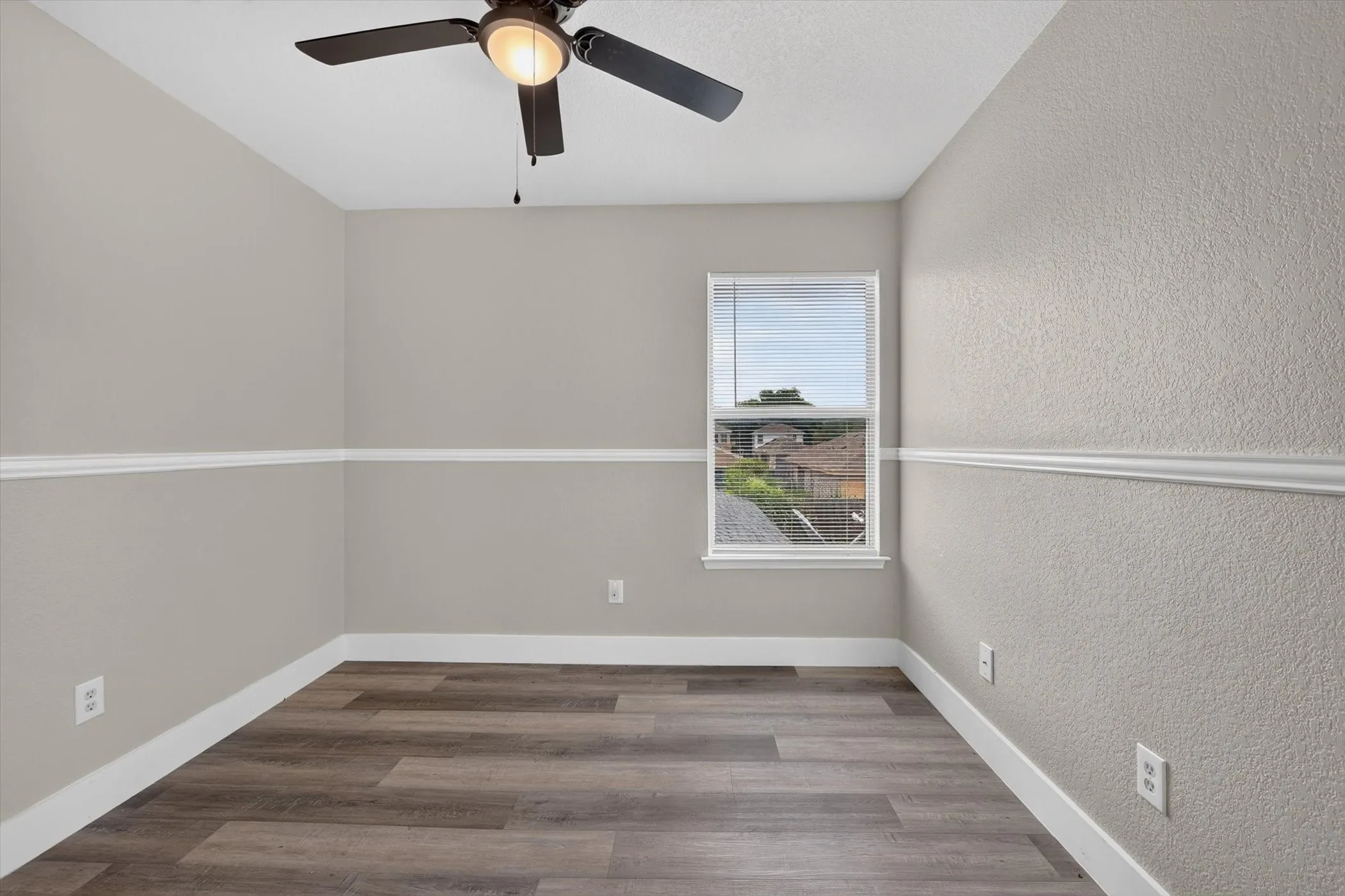 Room featuring wood-finish flooring, neutral paint tones, and white trim