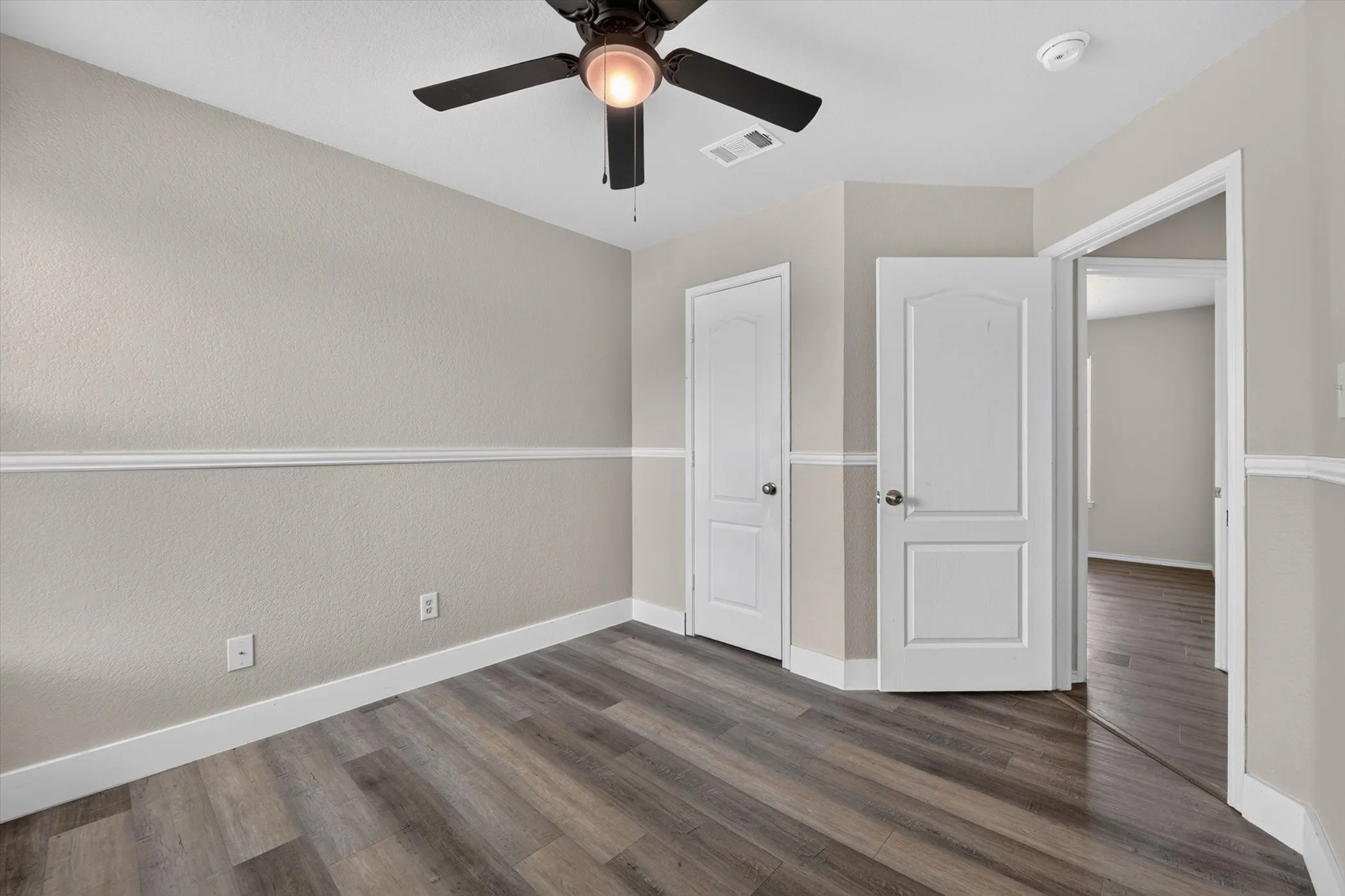 Room featuring wood-finish flooring, neutral paint palette, and white baseboards