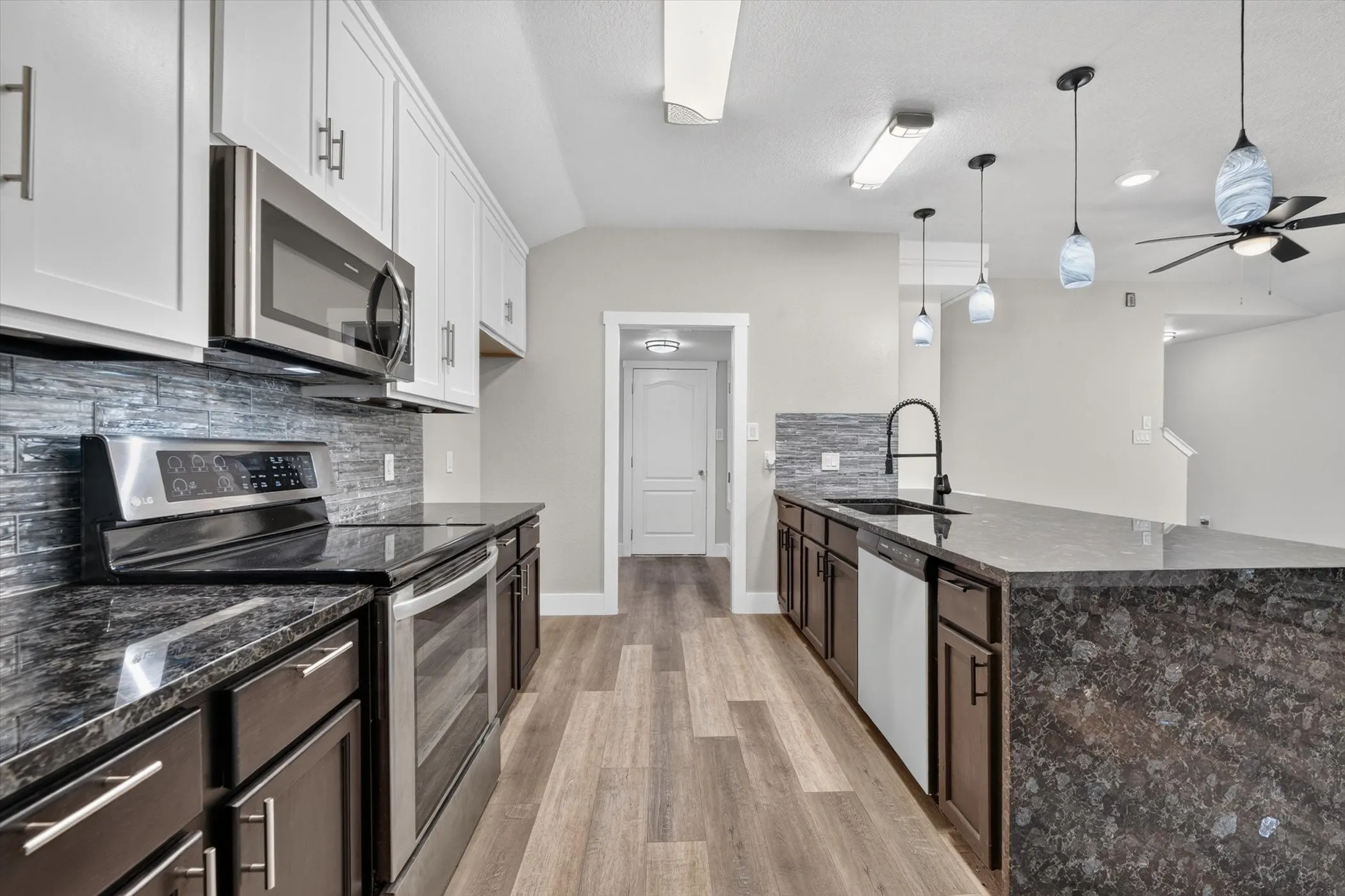 Contemporary kitchen featuring dark wood-finish lower cabinetry, white upper cabinetry, and stainless steel appliances