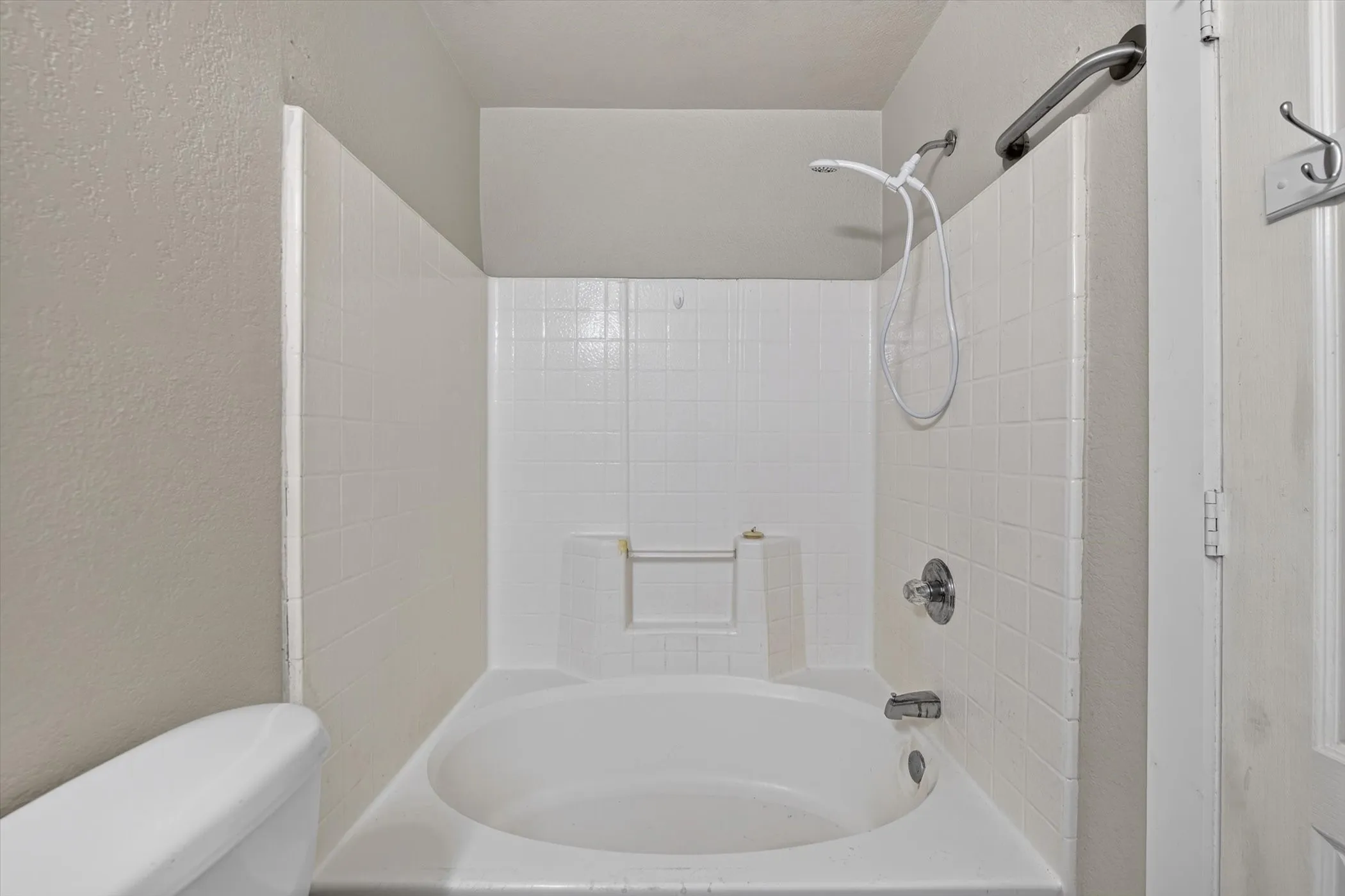 Alcove bathtub with white subway tile surround and integrated shower