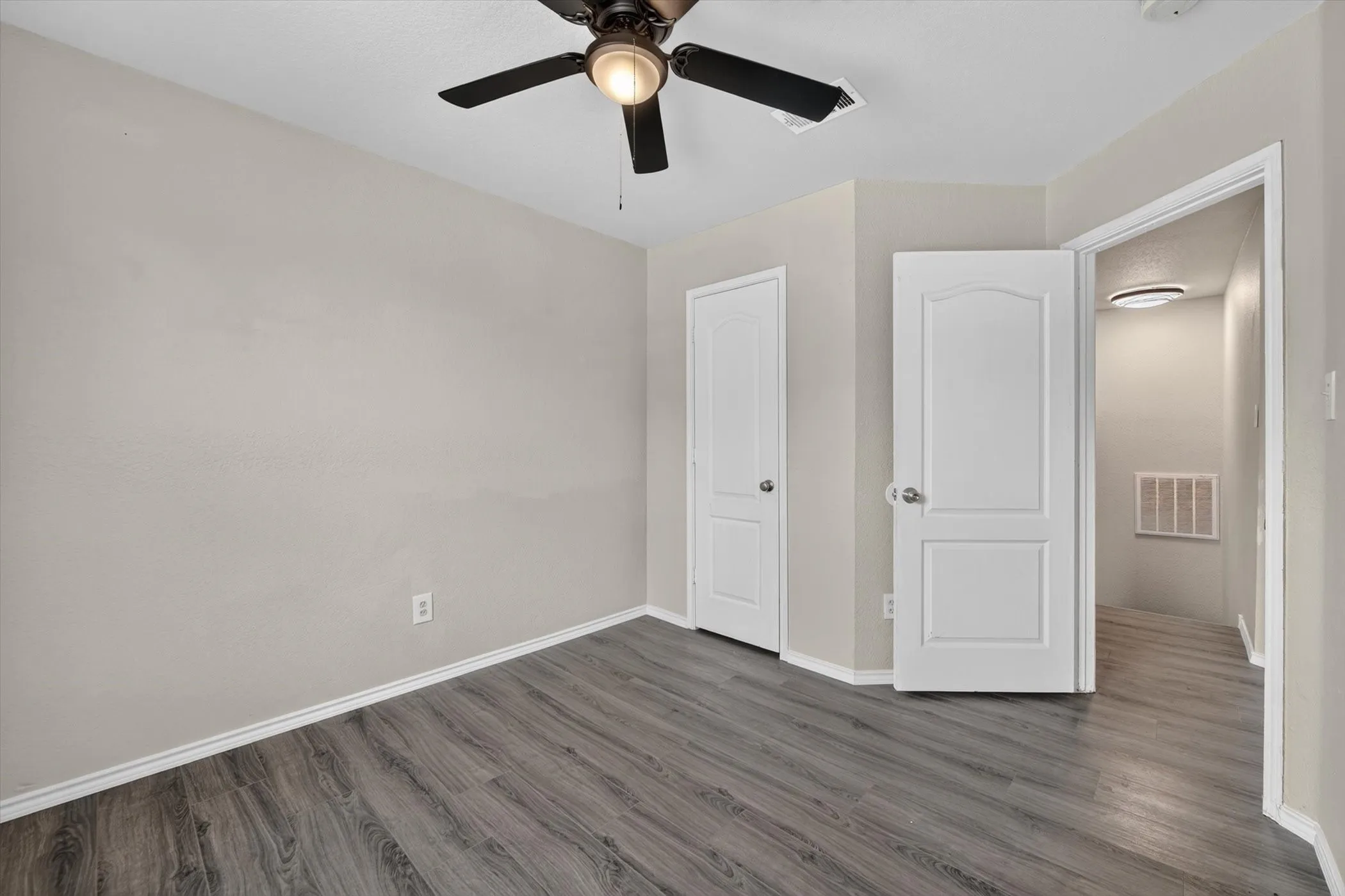 Room featuring wood-finish flooring, light neutral wall tones, and white trim