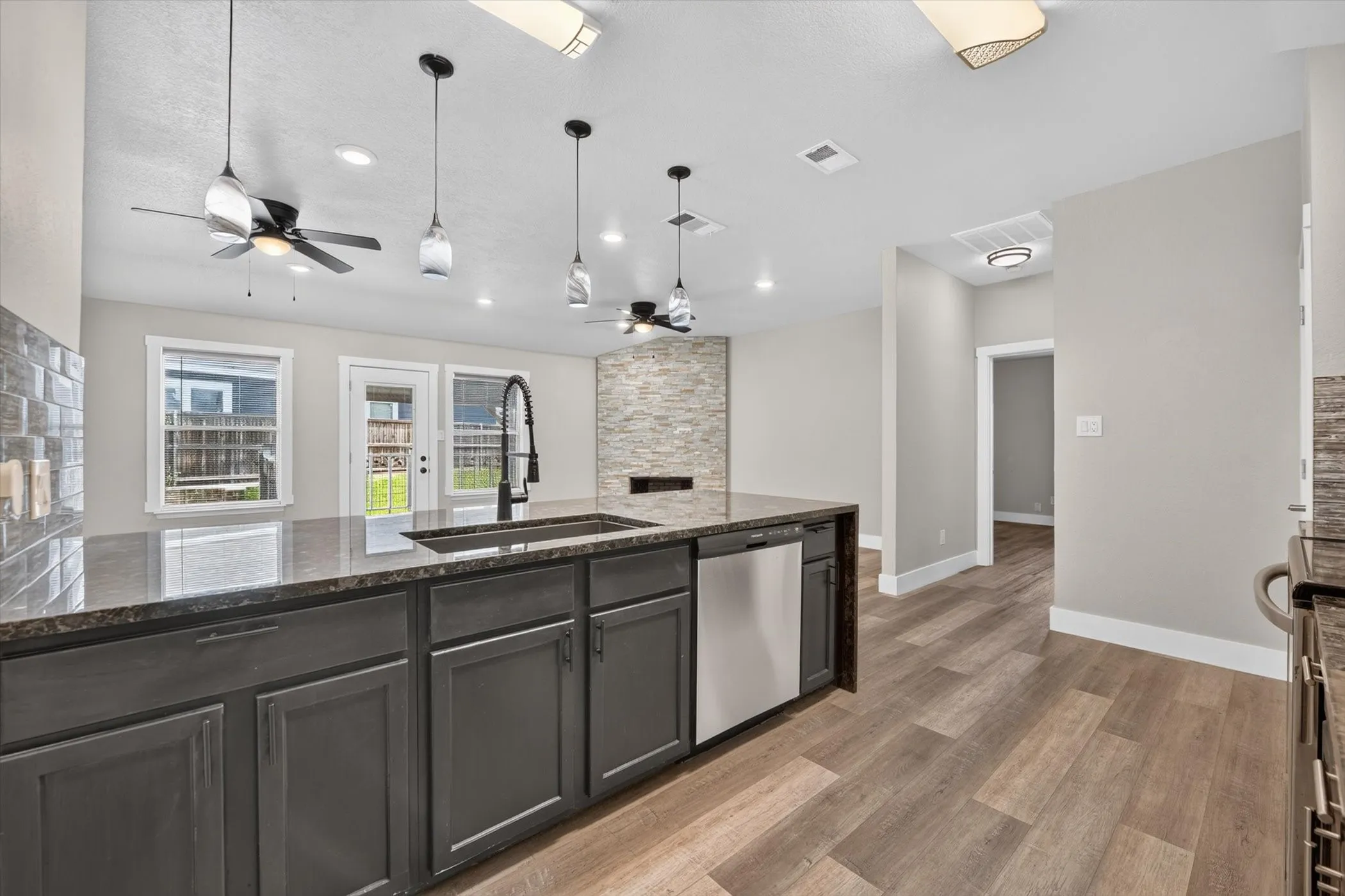Kitchen island featuring dark cabinetry, a built-in sink with a matte black faucet, and a dark stone countertop
