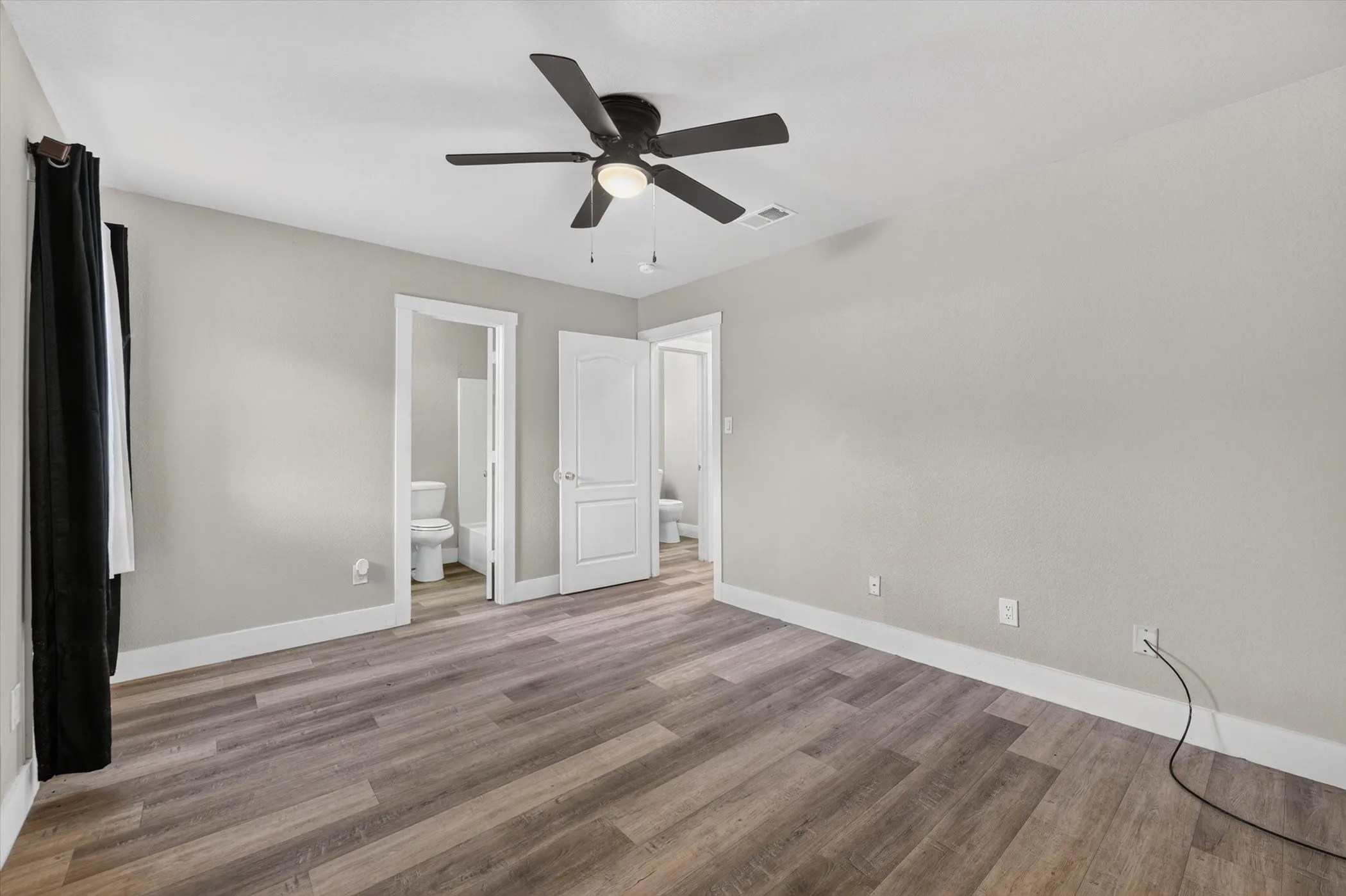 Spacious room featuring wood-finish flooring, light gray walls, and white baseboards