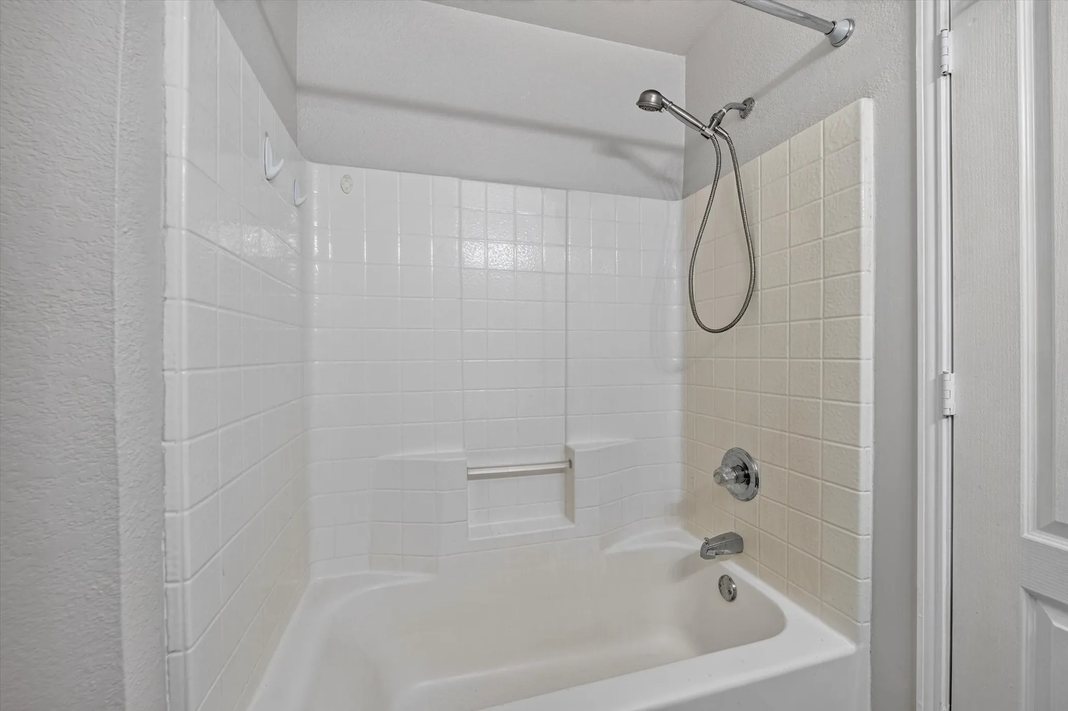 Full-size bathtub with a built-in shower, complete with a chrome showerhead and faucet